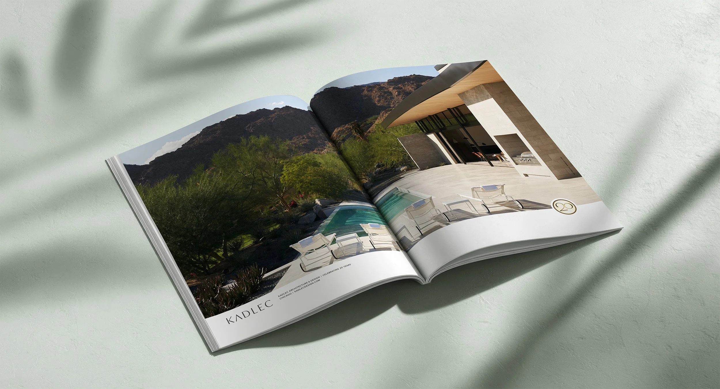 Open magazine showing an outdoor modern house with a pool, patio furniture, and a mountain landscape in the background.