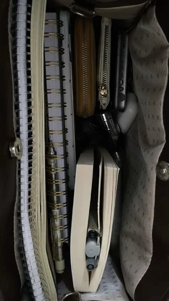 Un sac contenant des cahiers, des notes, un stylo, une lampe de poche, un casque audio et d'autres objets personnels.