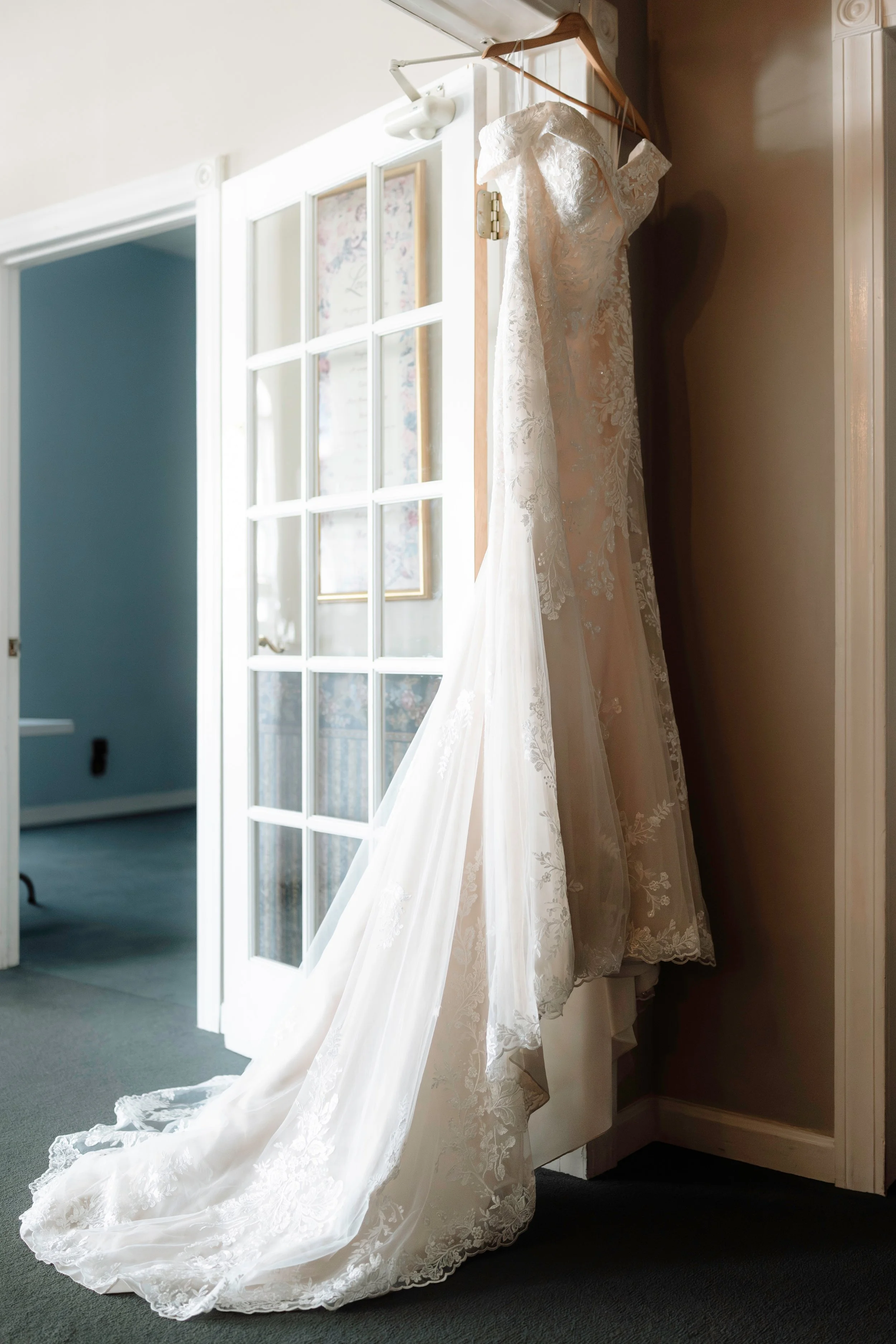 White wedding dress with a long train hanging indoors.
