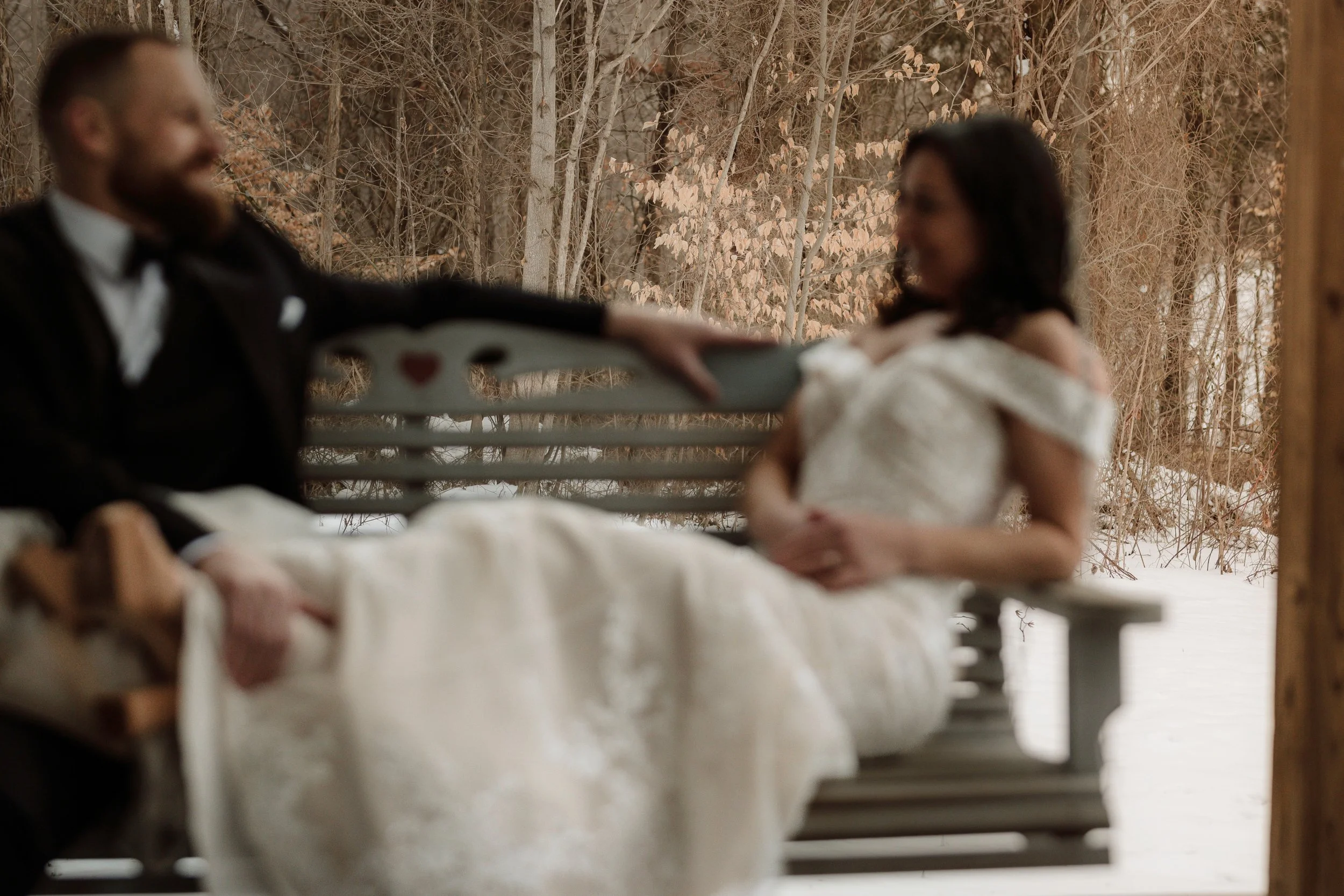 Romantic winter wedding photography of a happy couple sitting on a porch swing in the snow.