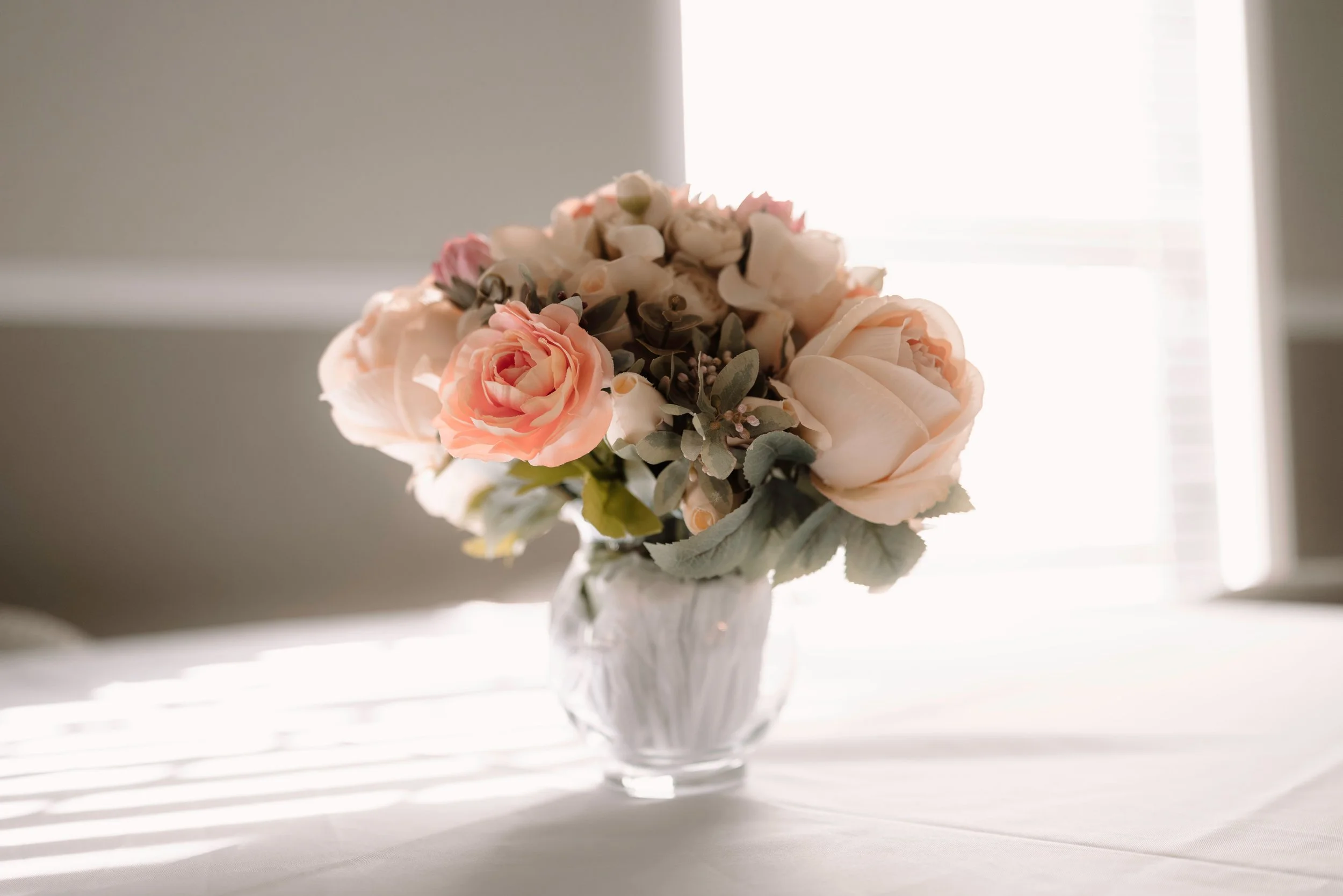 Small bouquet of white and peach flowers in a glass vase.