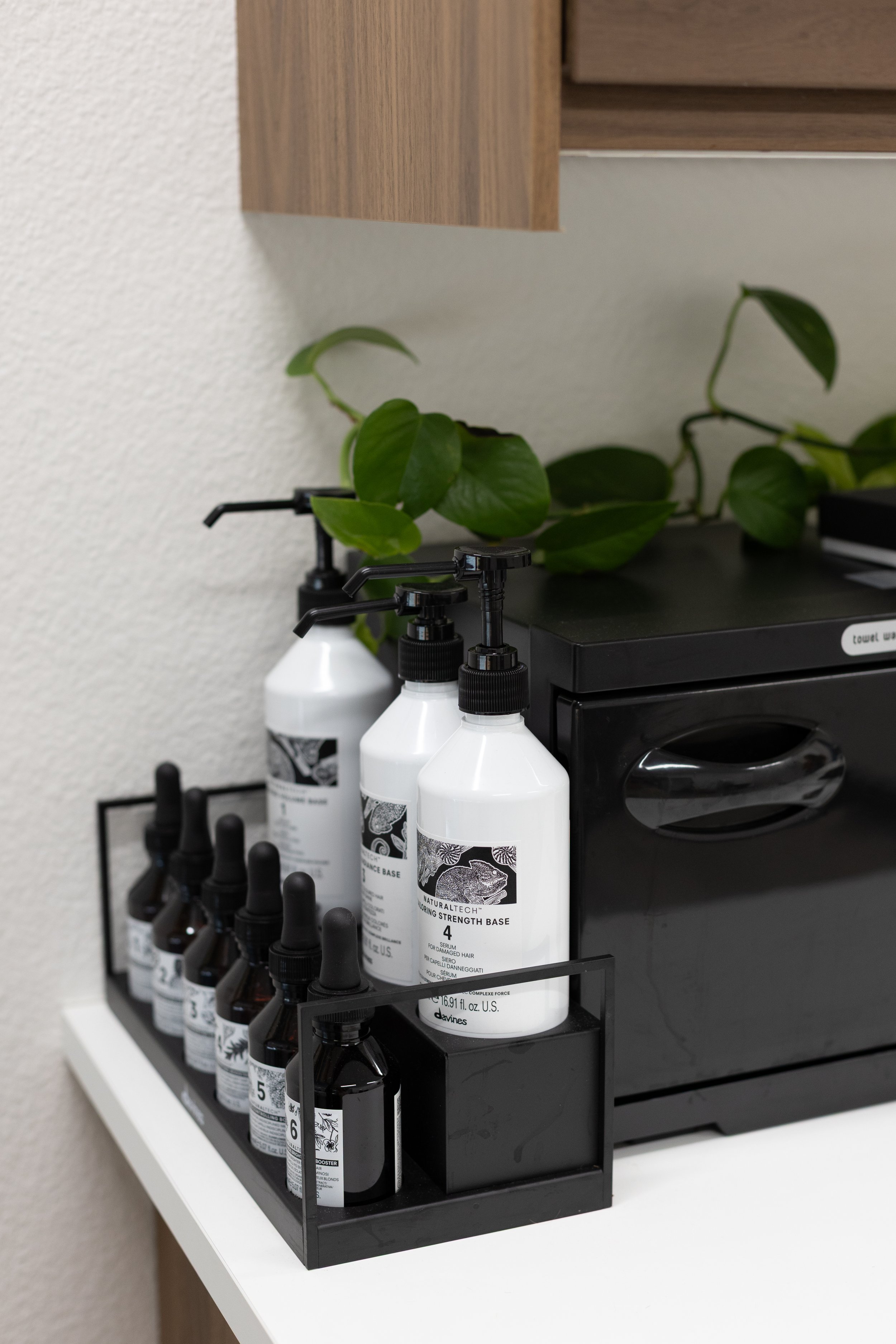 Various bottles and containers of hair products from the brand Davines, including MINU shampoo and DEDE conditioner, displayed on a shelf.
