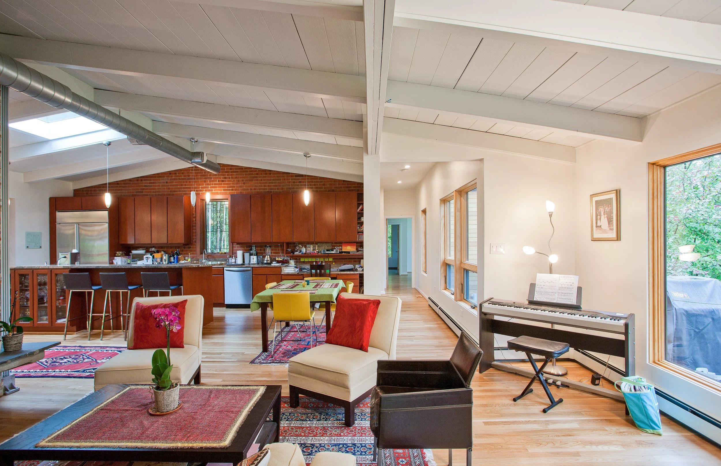 Open-plan living room and kitchen under a vaulted ceiling with skylights in a renovated mid-century home