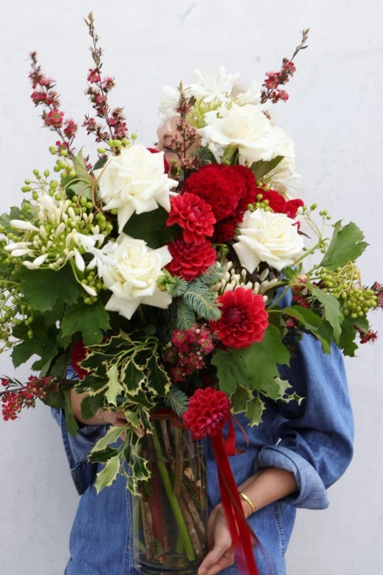 Close-up-Christmas-vase-arrangement-with-holly-spruce-and-red-and-green-and-white
