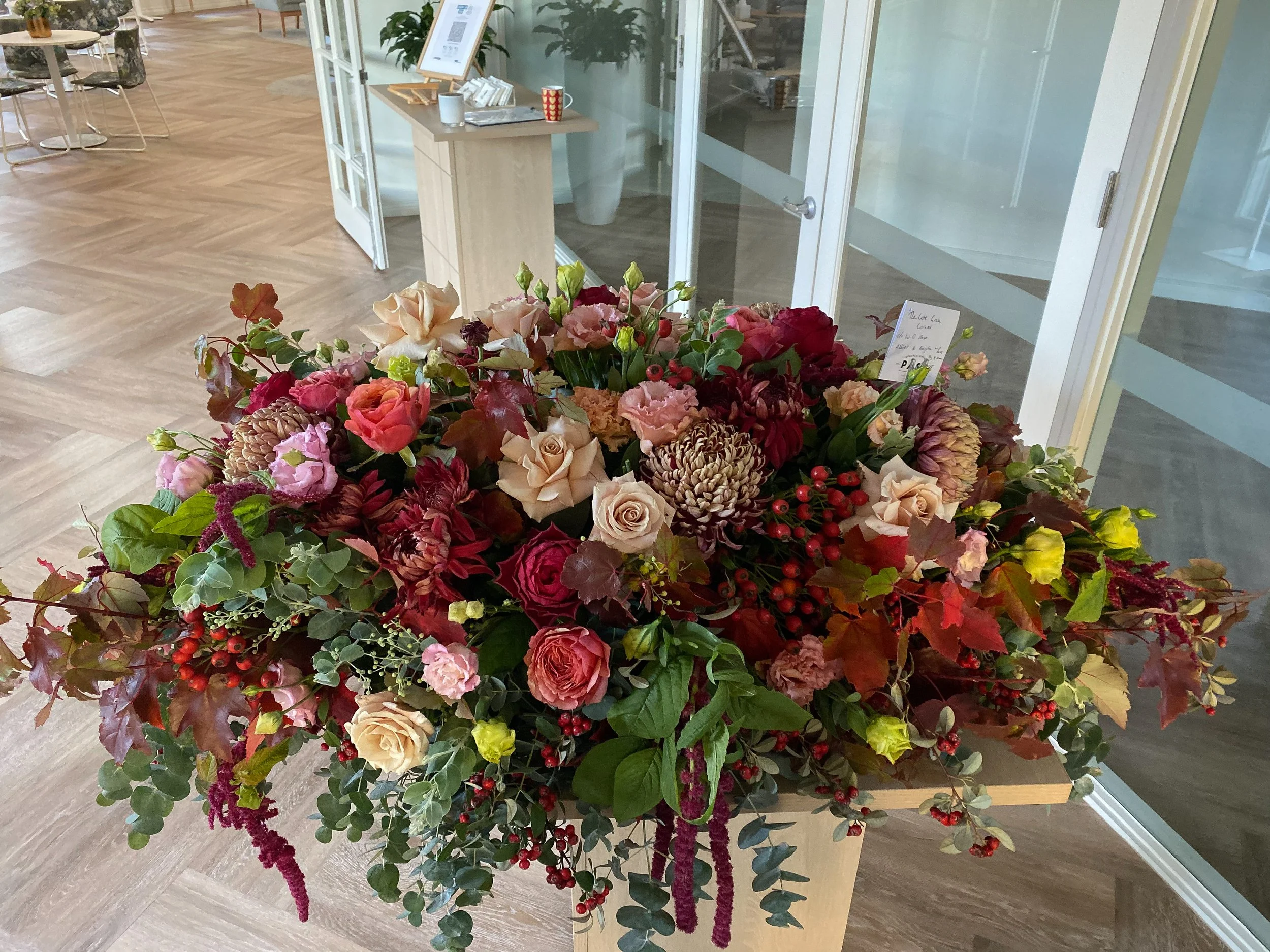 Garden-style autumn funeral casket spray created with fresh seasonal flowers in warm autumn tones by Pash Flowers, Brighton florist specialising in bespoke funeral flowers.