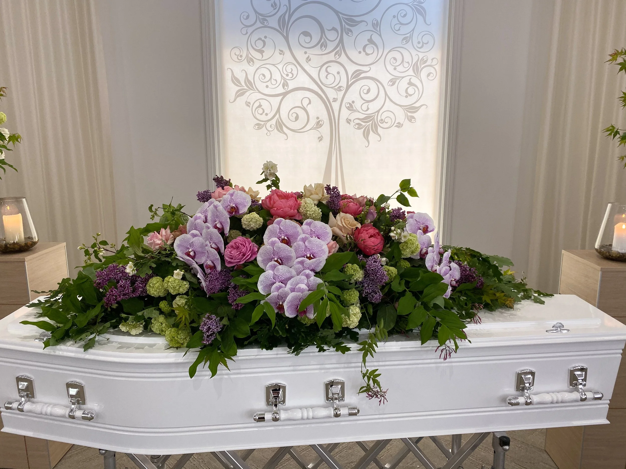 Elegant funeral flowers including a handcrafted casket spray with white roses, lisianthus and seasonal foliage by Pash Flowers Melbourne.