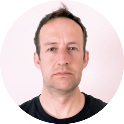 A man with short dark hair and a serious expression, wearing a black shirt, against a white background.