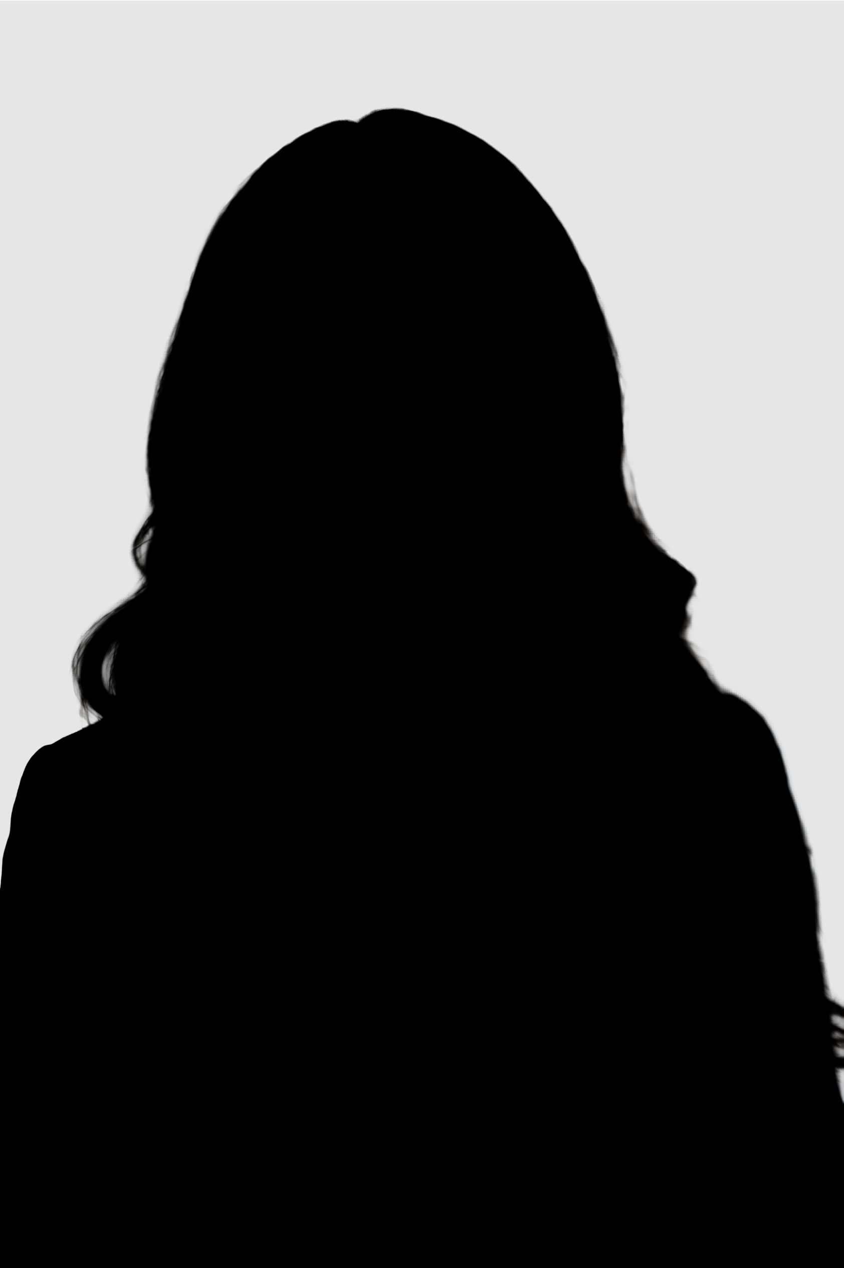 Black and white portrait of a young woman with short curly hair, freckles, hoop earrings, and a nose piercing, looking directly at the camera against a plain dark background.