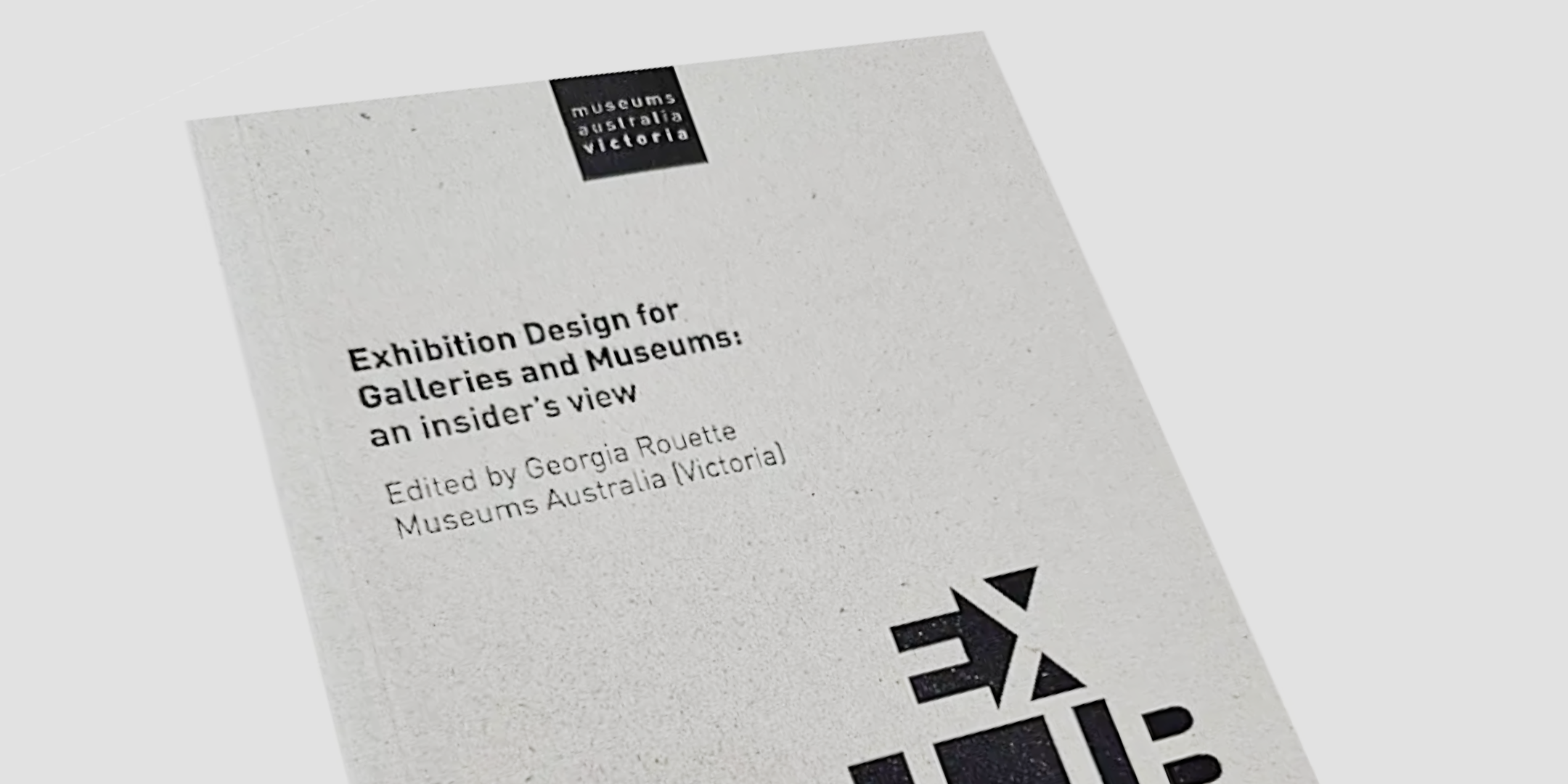 Book cover titled 'Exhibition Design for Galleries and Museums: an insider's view', edited by Georgia Rouette, Museums Australia (Victoria), with a minimal black and white geometric design on a textured beige background.