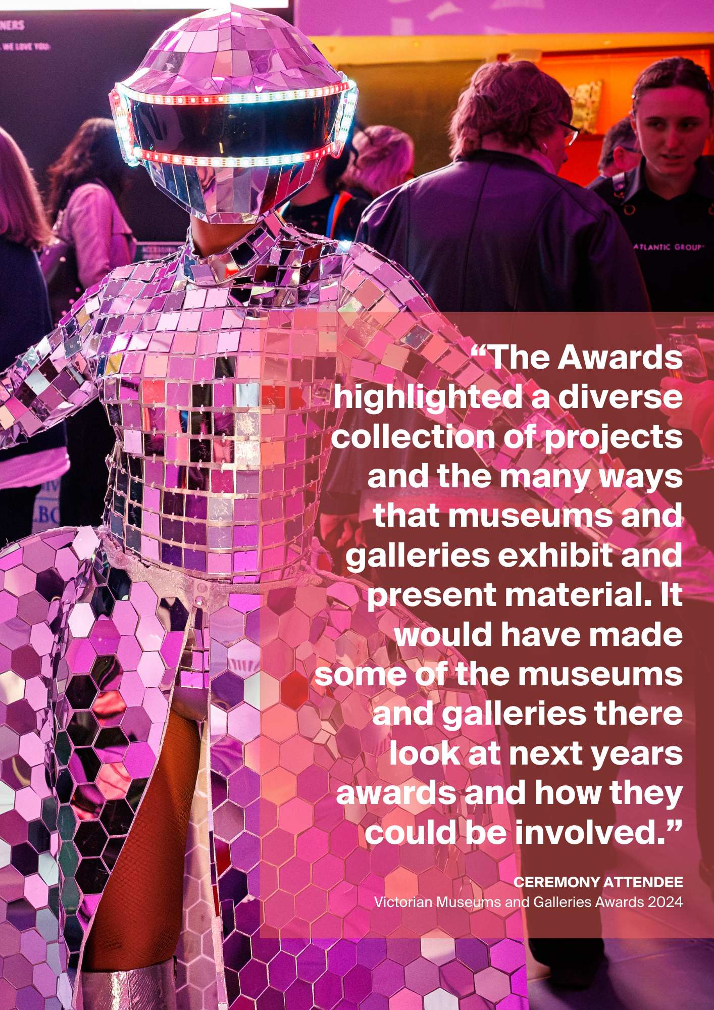 A person in a costume stands in front of a crowd, a quote in white text against a red, transparent background is overlaying the image.