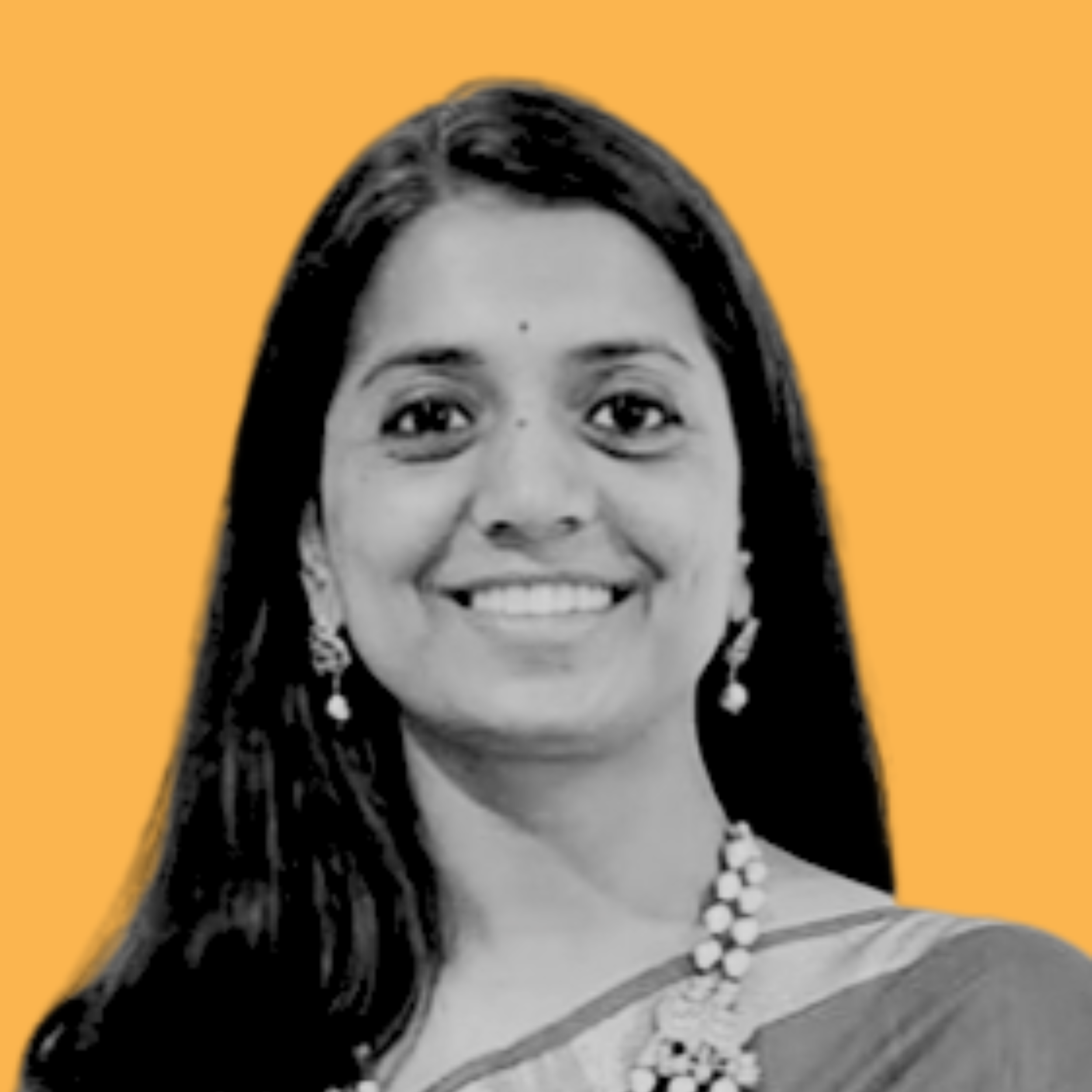 Black and white portrait of a woman with curly hair wearing glasses, smiling, with an orange background.
