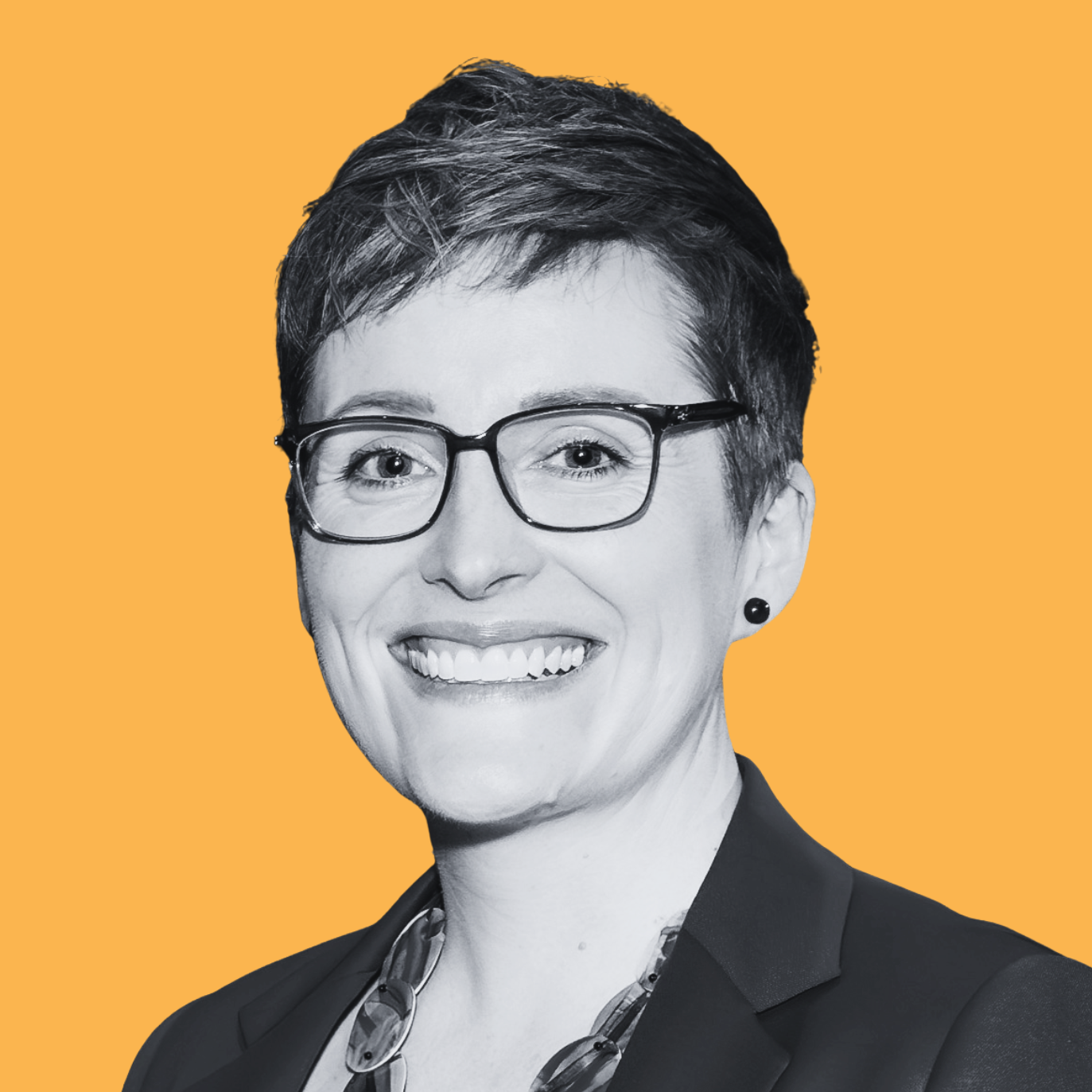 Black and white portrait of a smiling woman with short hair, wearing a patterned top and dark blazer, against an orange background.