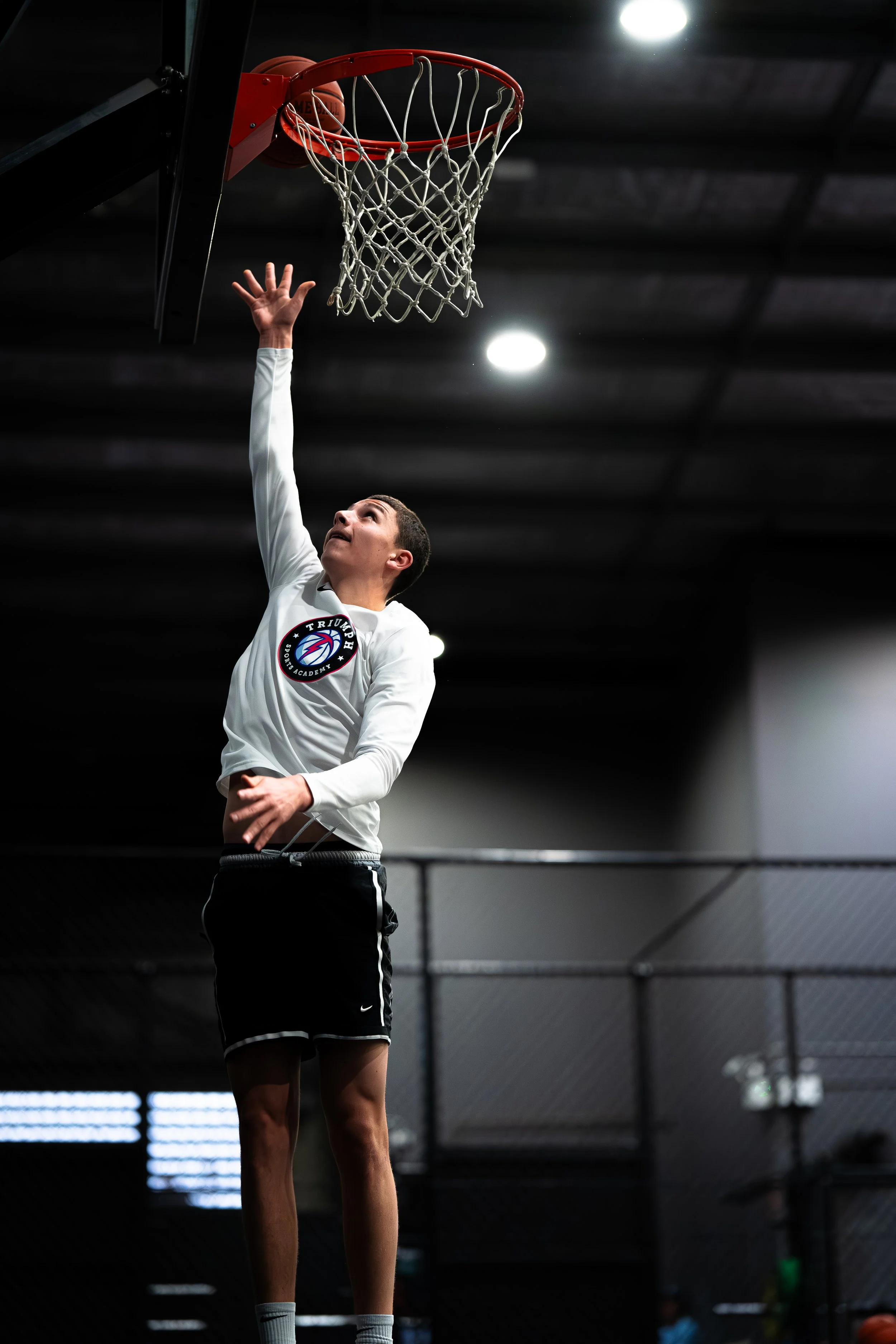 Young male basketball player attempting a shot in a gymnasium.