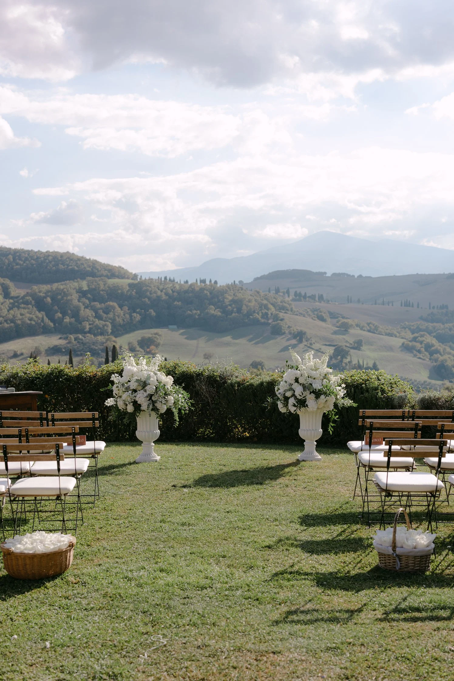 White flower arrangements and chairs set up for a Tuscany wedding ceremony by Toscoana at Terre di Nano
