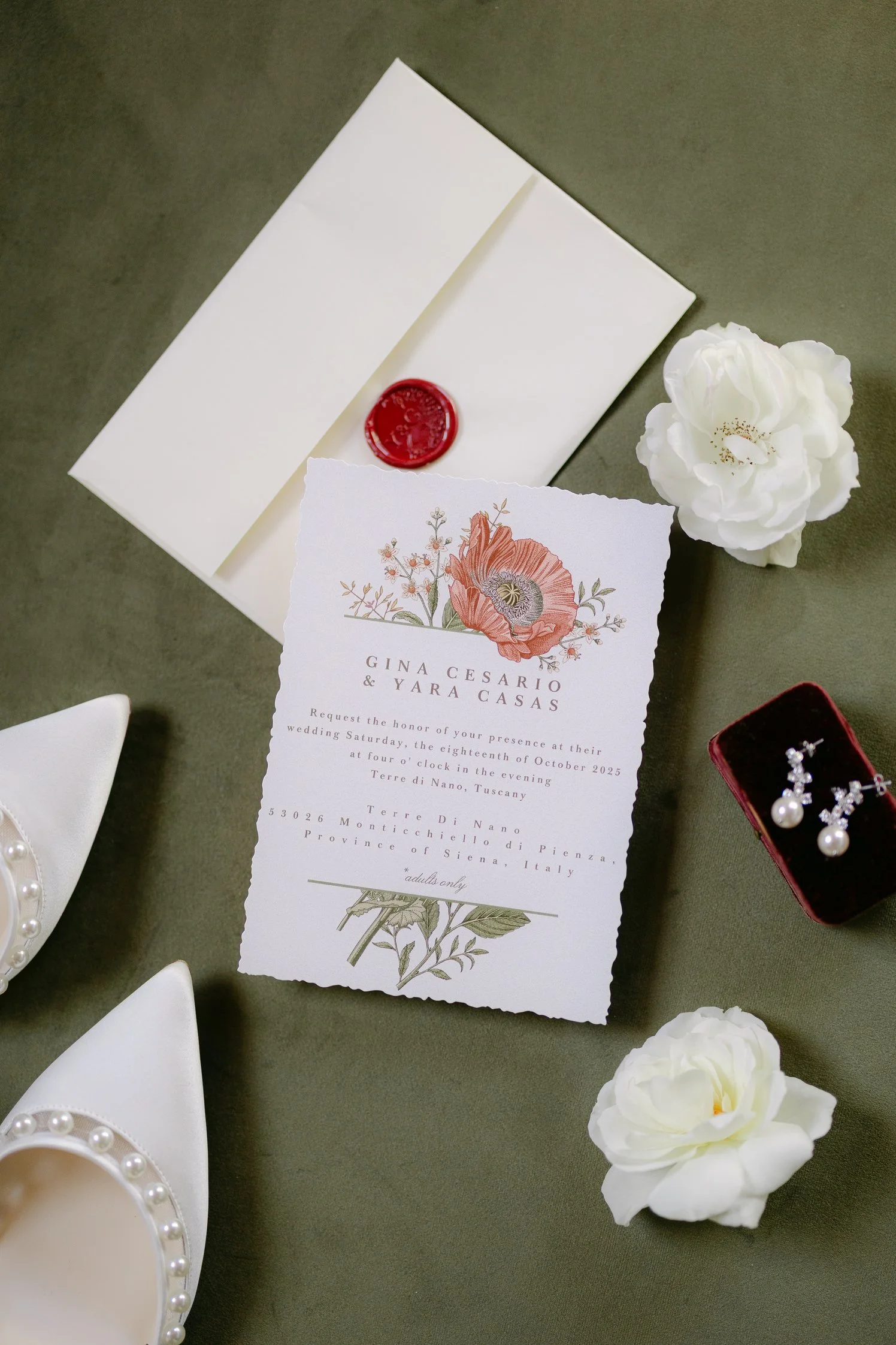 Elegant wedding invitation flatlay with white flowers, grapes, and rings