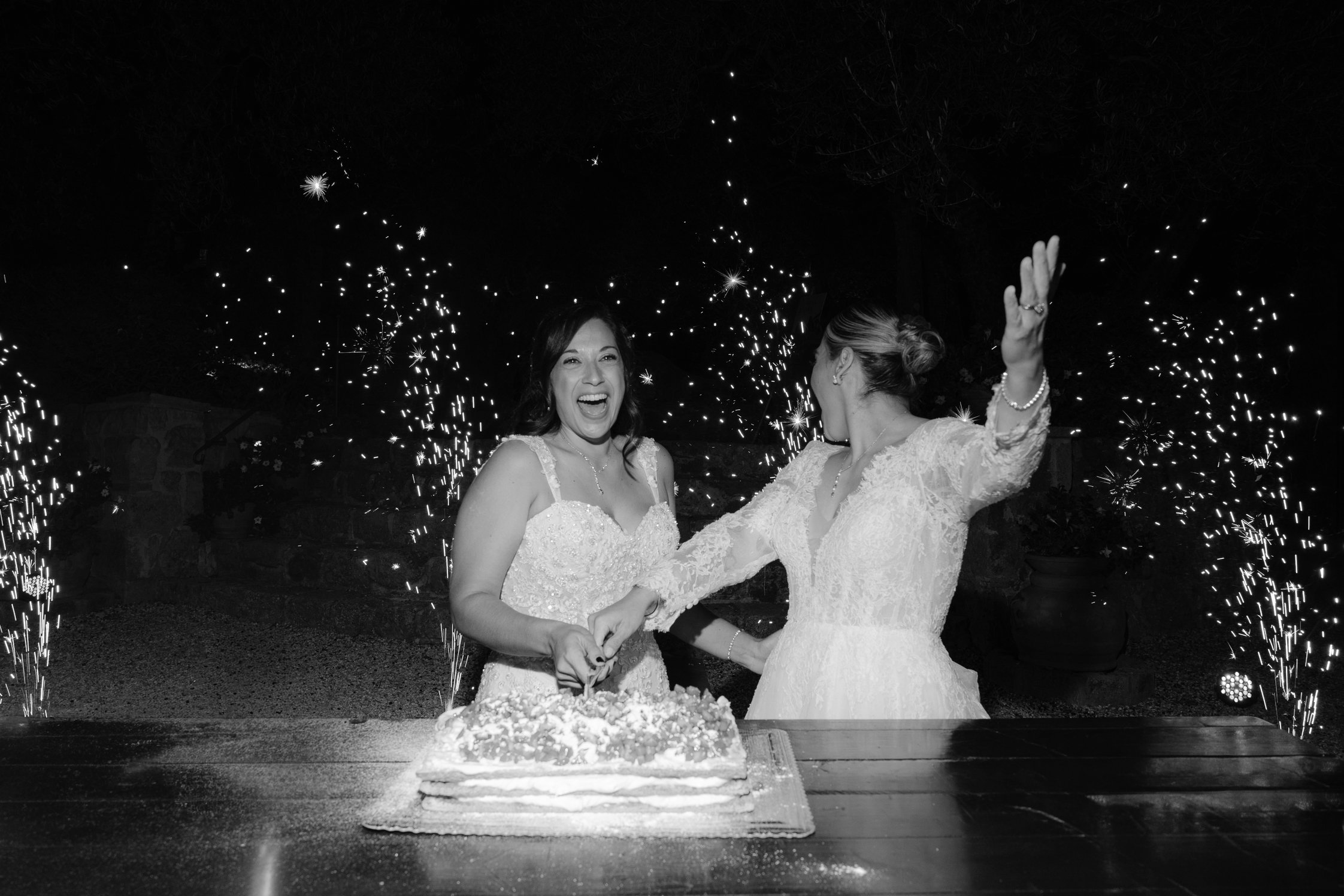 Two brides preparing a millefoglie cake during their Tuscany wedding.