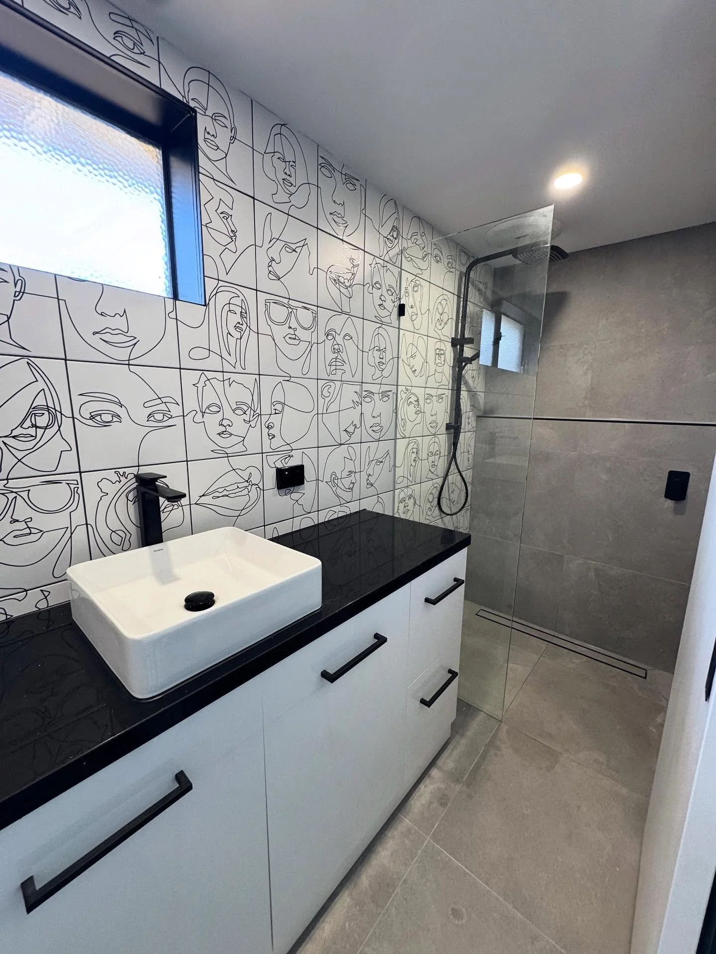 Bathrooms don&rsquo;t need colour to have character.

This renovation balances a quiet grey envelope with a bold line-art feature wall, integrated black fixtures and a streamlined walk-in shower &mdash; creating a space that feels modern, expressive 