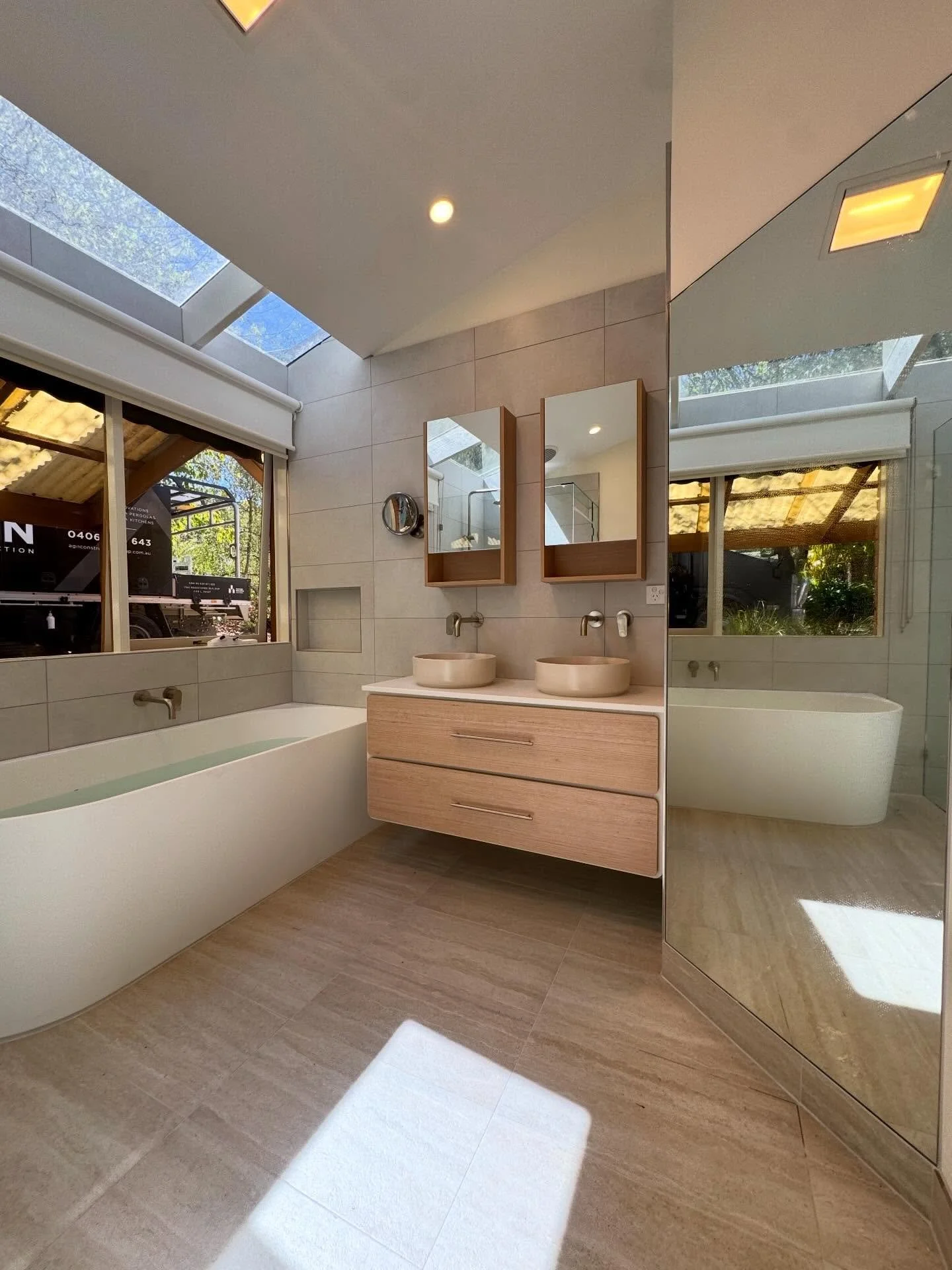 This bathroom renovation is all about creating a calm, spa-like space with a modern edge. 
The skylights flood the room with natural light, perfectly complementing the warm timber vanity and soft neutral tones.

Featuring:
&bull; Freestanding bath po