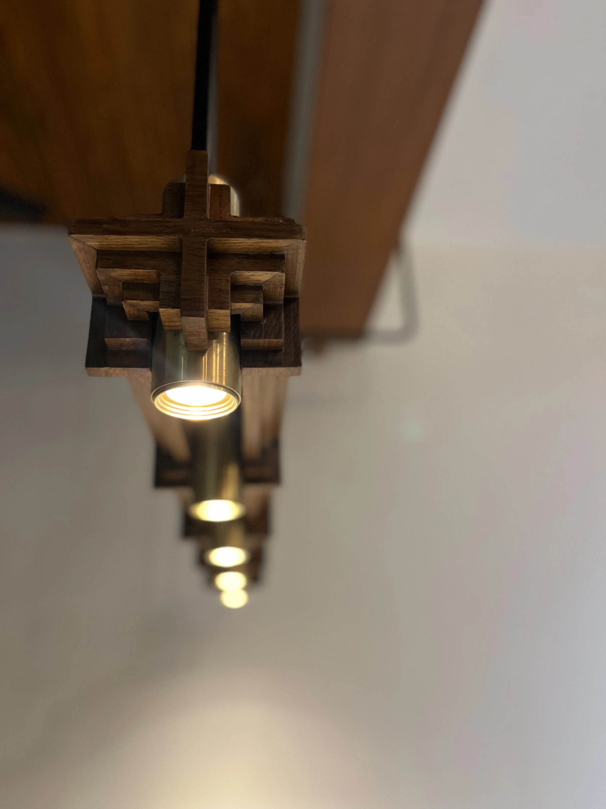 Close-up of modern pendant lights with wooden accents hanging in a row, soft focus background.