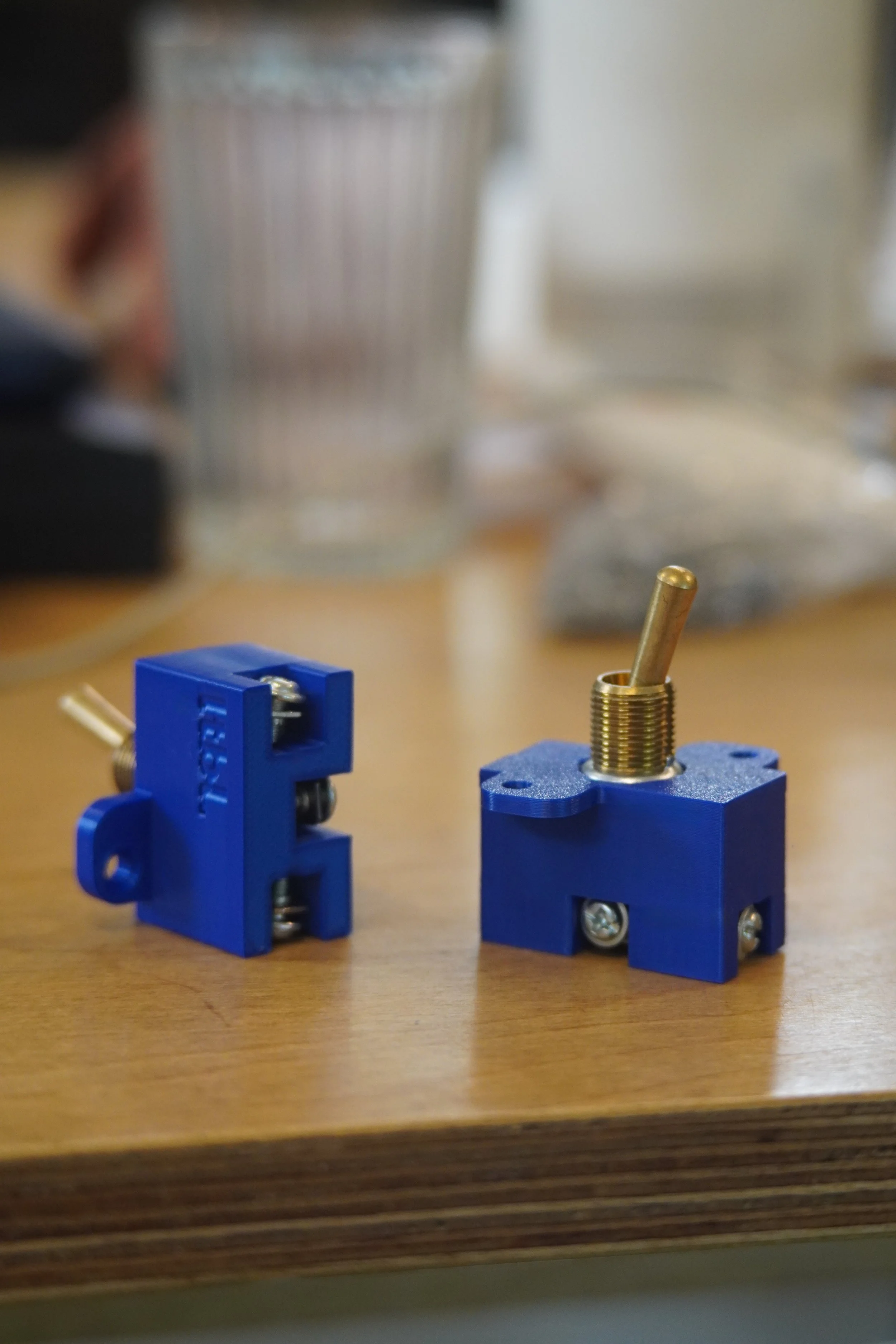 Two blue and gold mechanical parts on a wooden surface with a blurred background.
