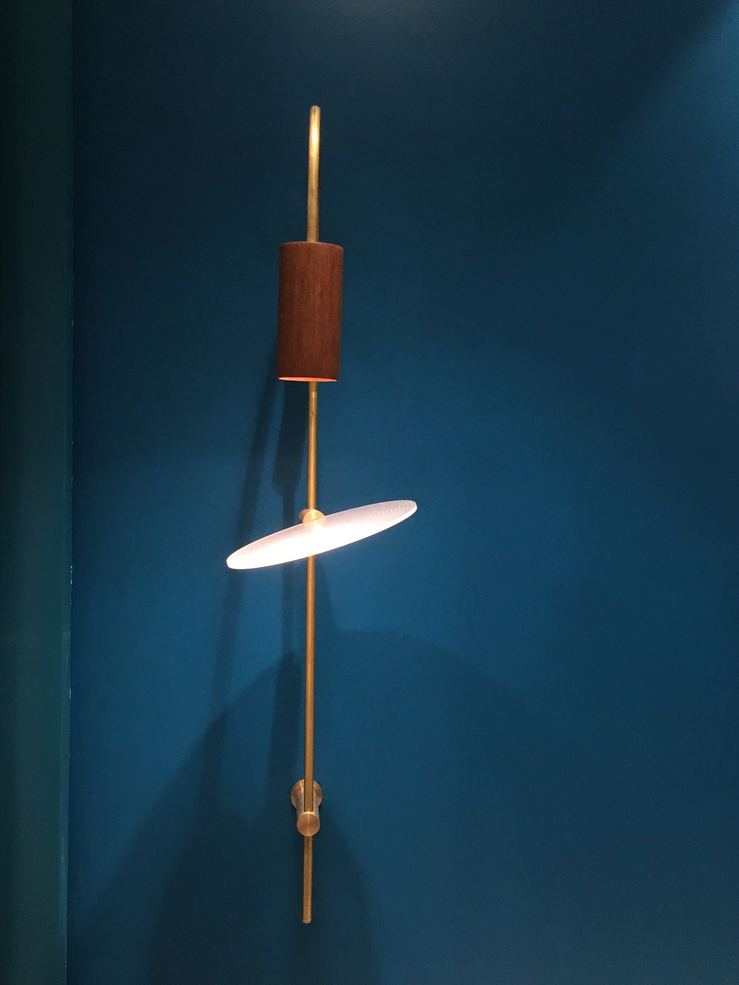 Modern wall sconce with brass details against a blue wall
