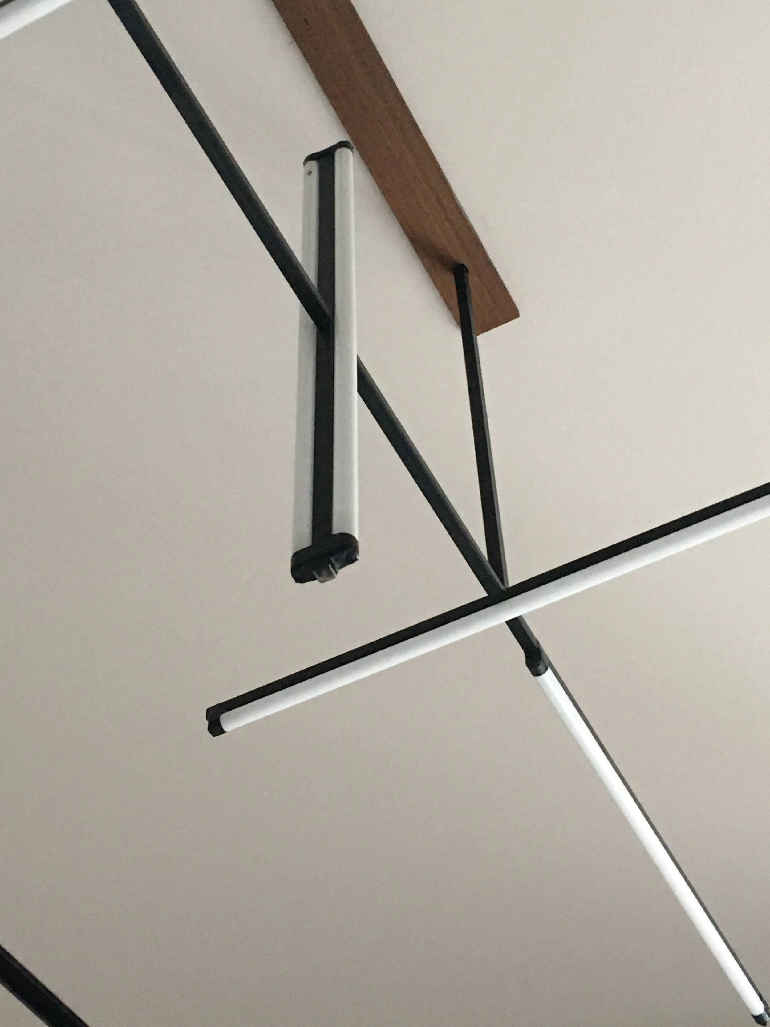 Modern ceiling light fixture with black and white rods and wooden accent.
