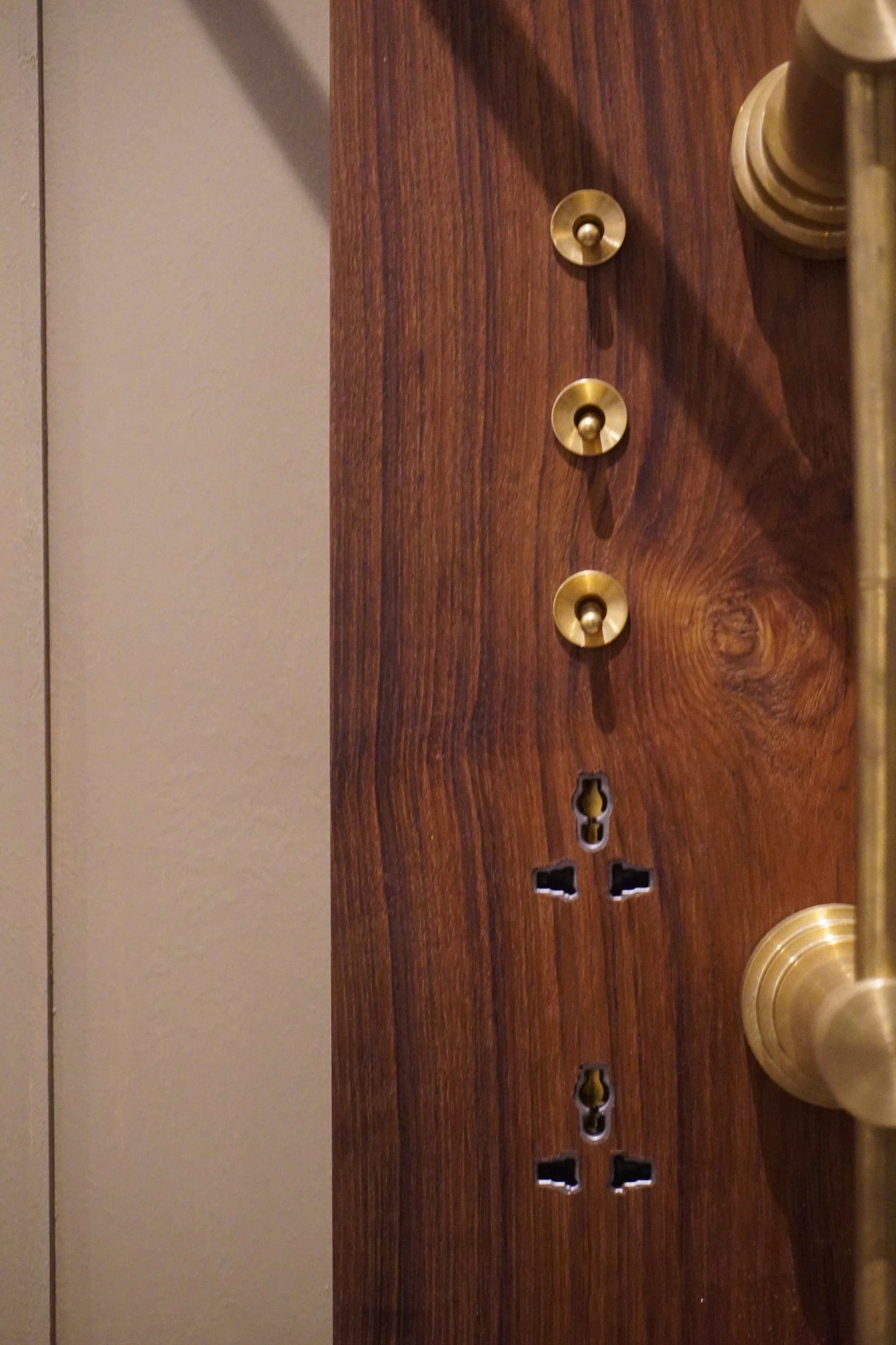 Close-up of a wooden door with brass knobs and keyhole cutouts, featuring a brass handle on the right side.