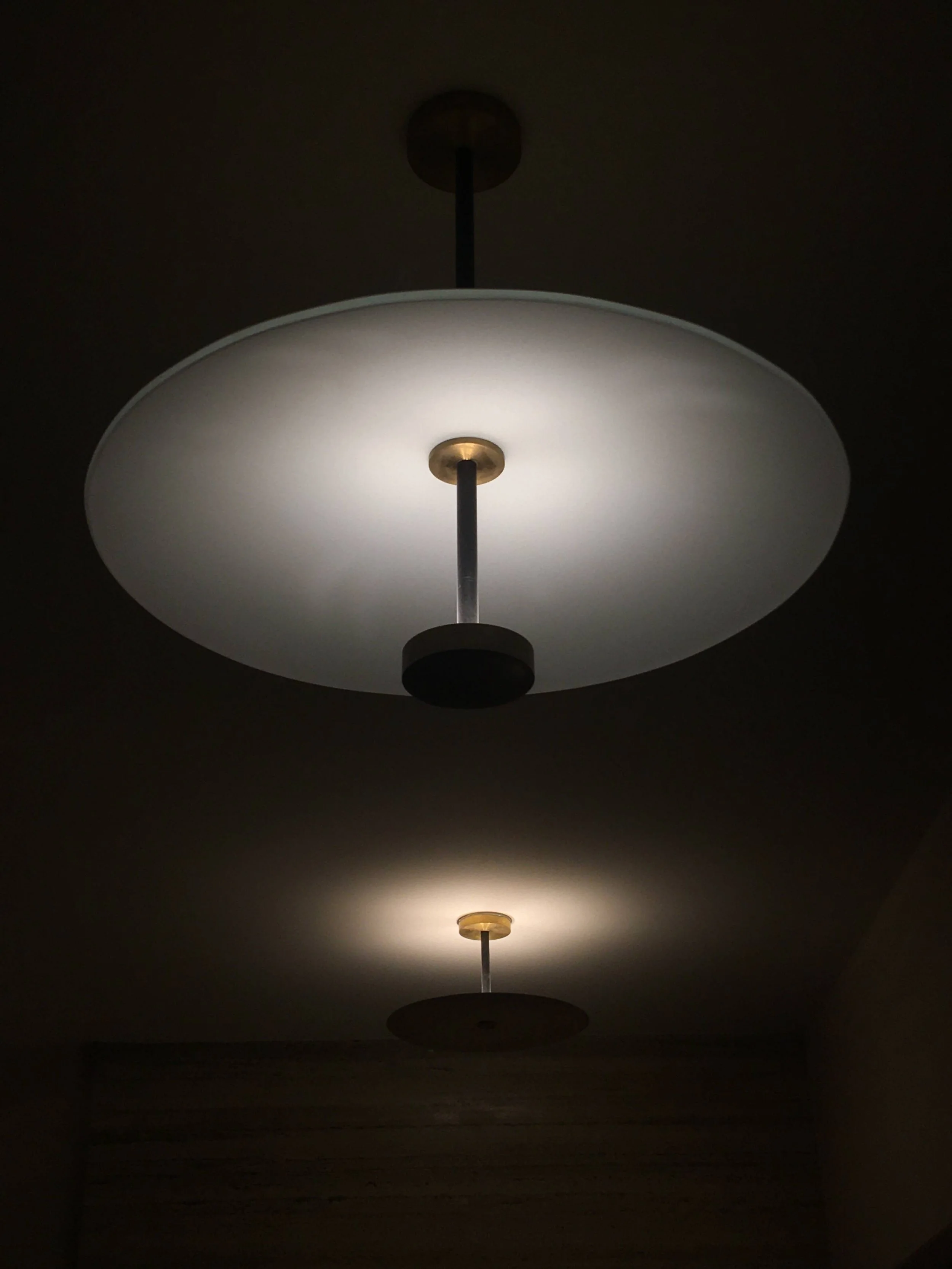 Ceiling lights with a modern, disk-like design glowing in a dimly lit room.