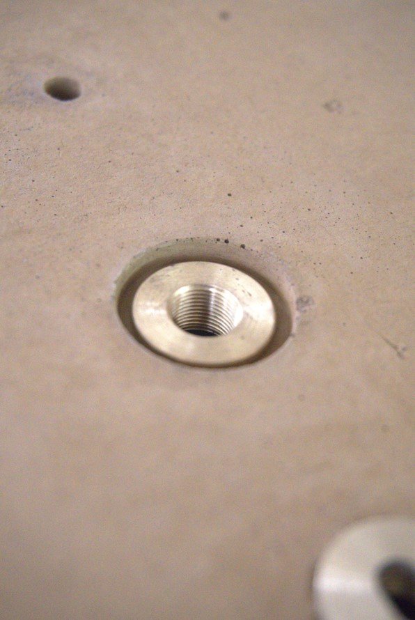 Close-up of a metal threaded insert embedded in a concrete surface