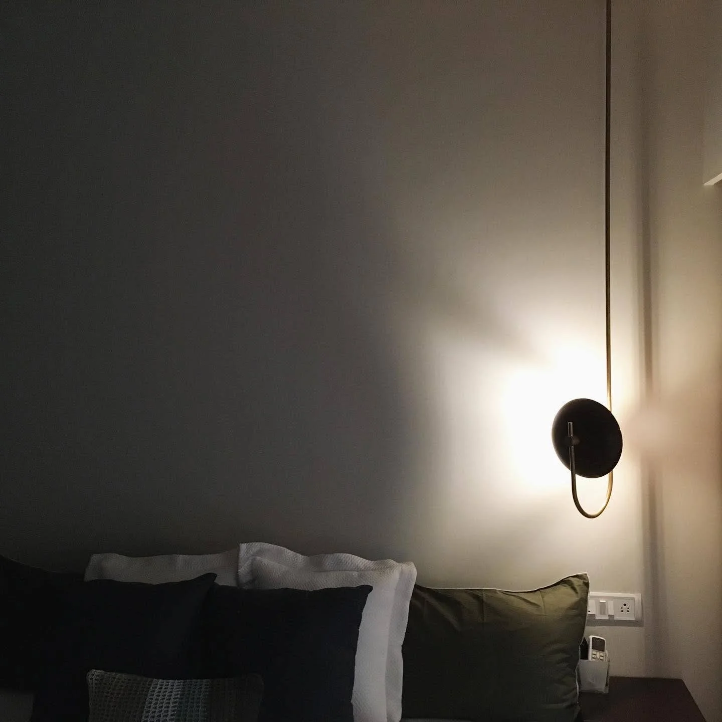 Bedroom with wall-mounted lamp, cushions, and power outlet