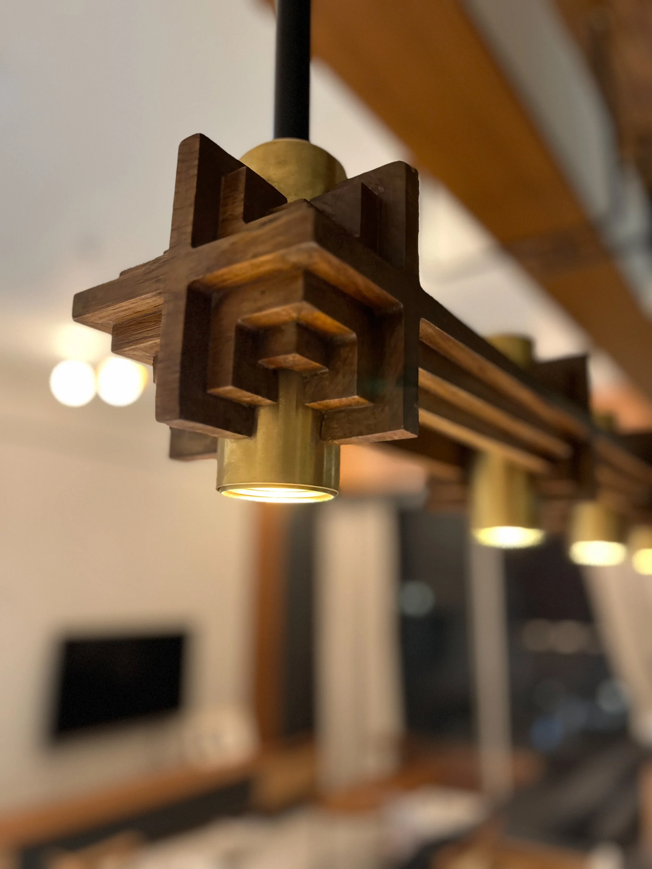 Close-up of a modern, geometric-style pendant light fixture in a living room setting.
