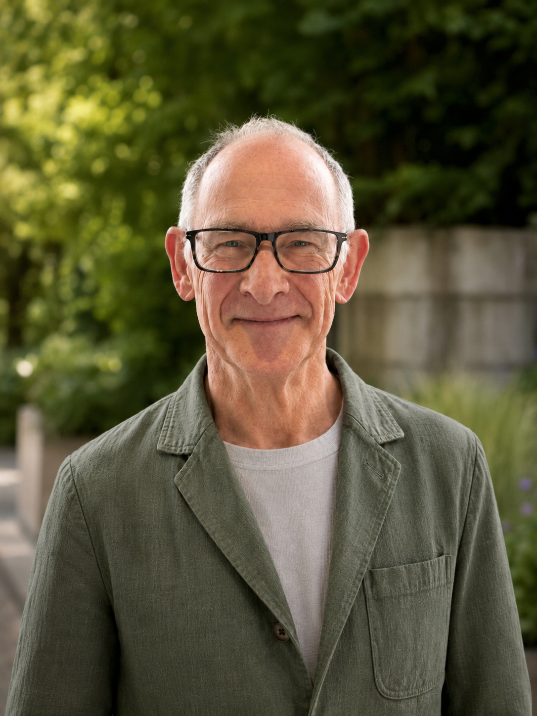 Elderly man with glasses, smiling, wearing a green shirt