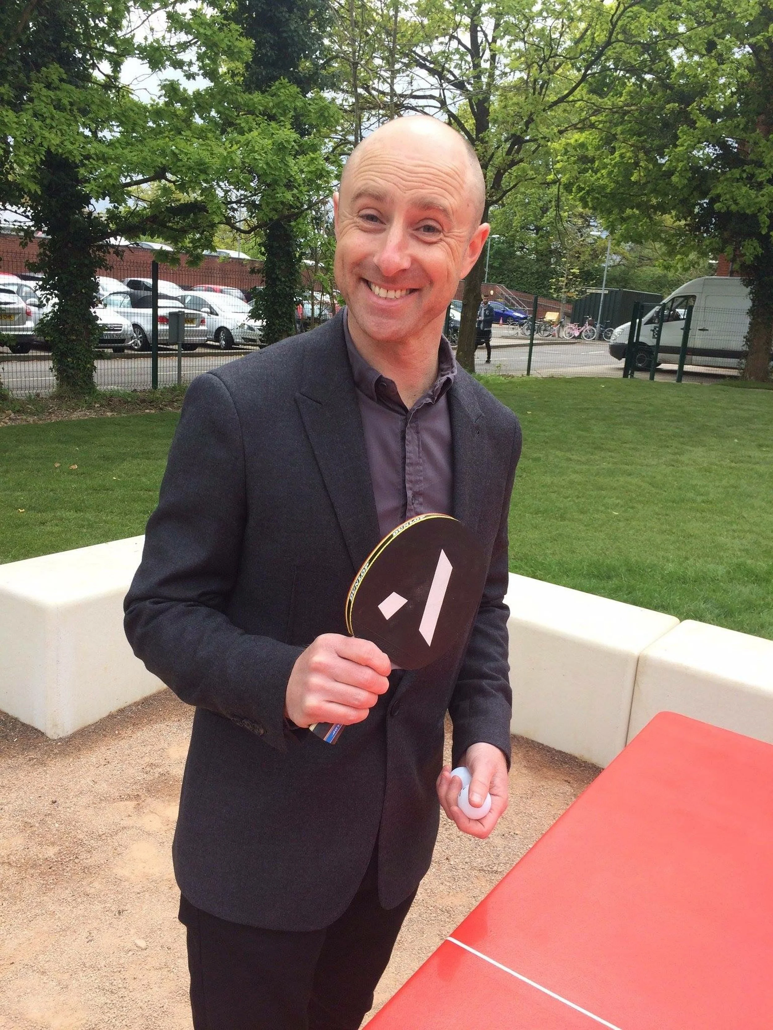 Person enjoying a playground zip line surrounded by trees and grass.