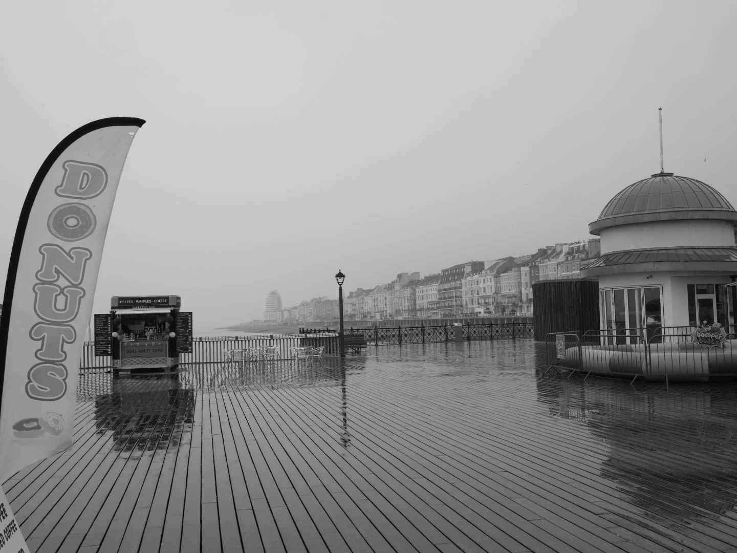 People scurry, they hide from grey. The quiet echoes of rain upon the pier.