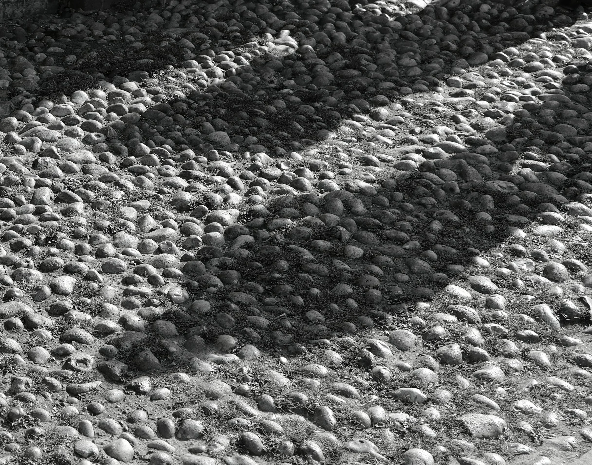 Shadows cast on cobbled ground, the fortress city high above the forgotten sea.