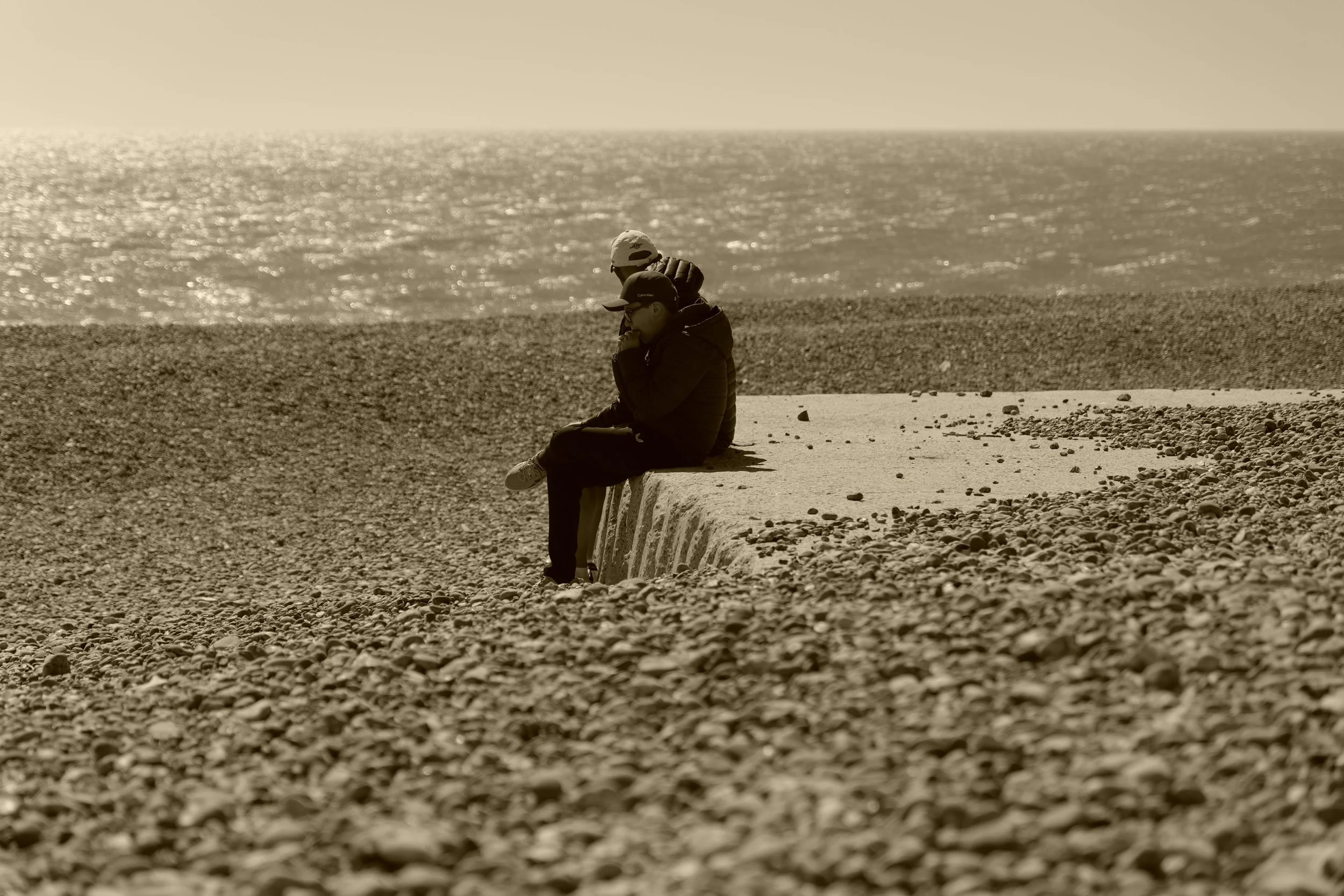 Bright is the light that shines on sparkled sea. They sit upon the land and share the time that wears against the stones.