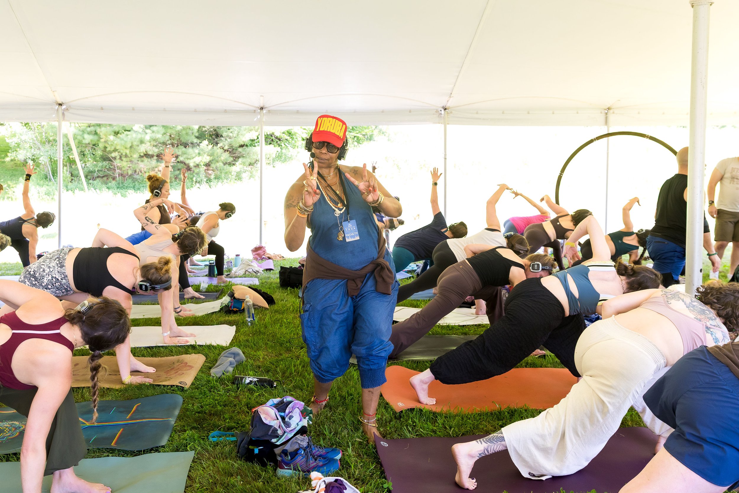 Yoga teacher Jyll Hubbard Salk giving the peace sign while instructing a group of yoga students under a tent