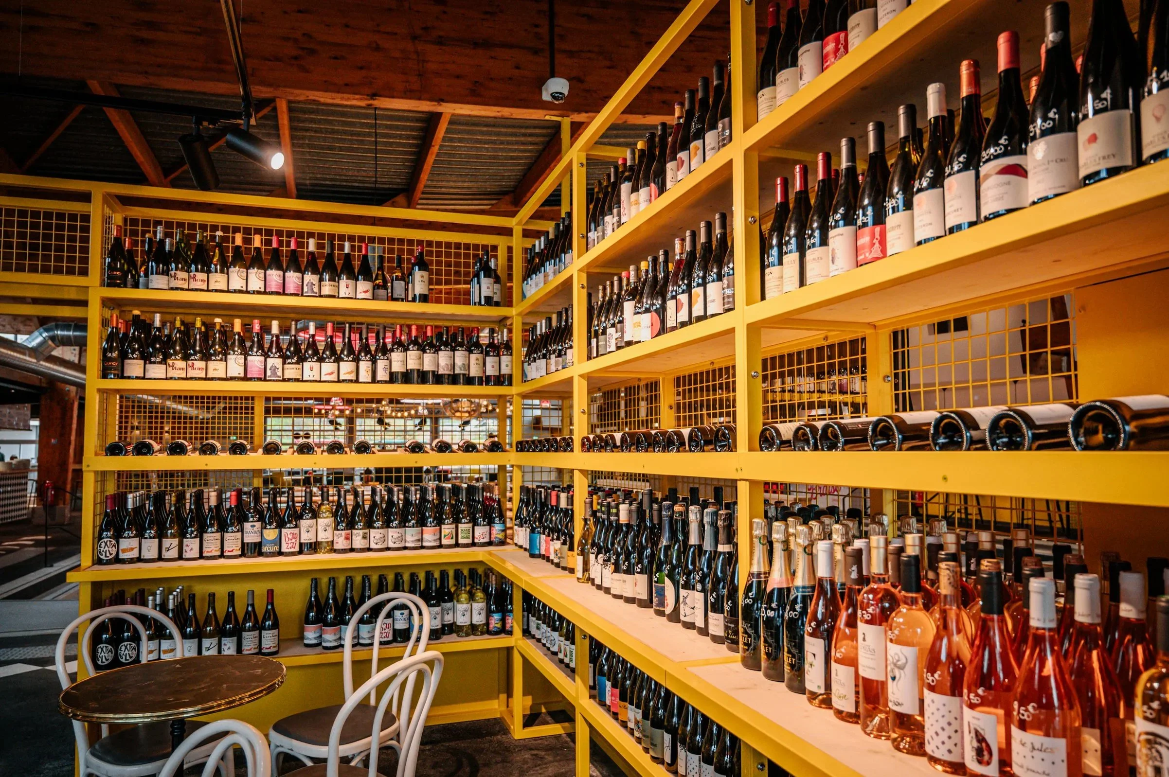 Rayonnages de bouteilles de vin dans un bar ou une cave avec meubles en bois et chaises blanches