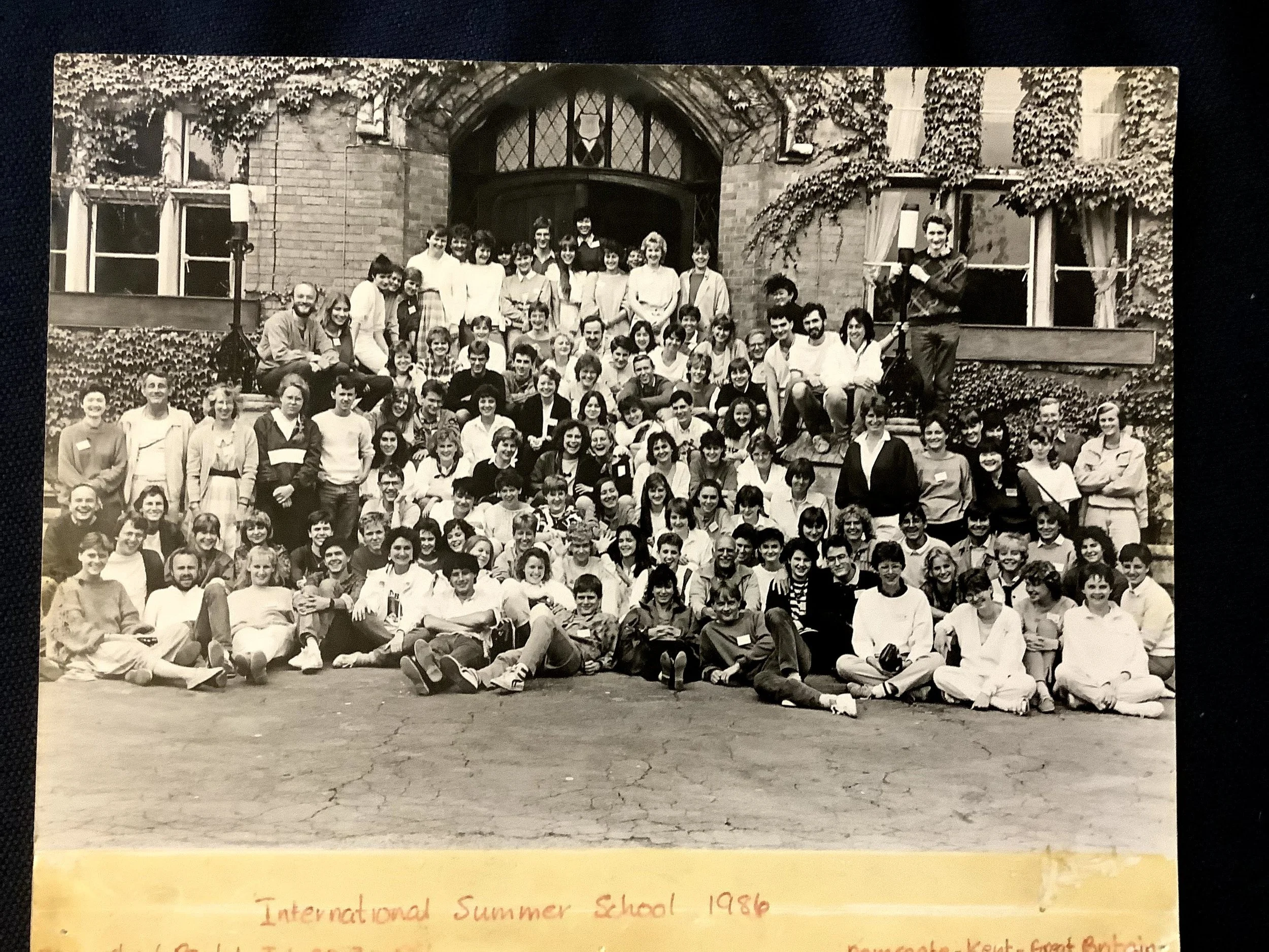a large group of people gathered in front  of a vine-covered building.