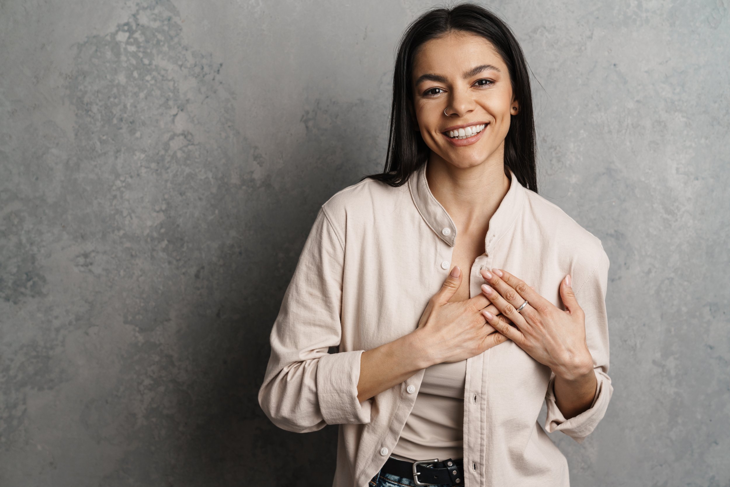 Mujer sonriendo con las manos en el pecho, imagen representativa de autoestima saludable, amor propio y bienestar emocional.