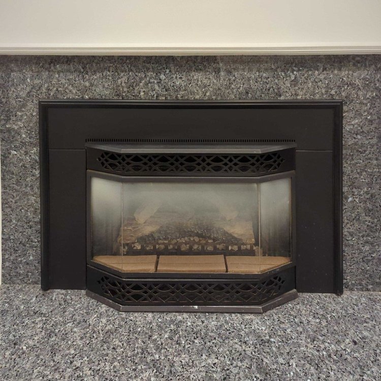 Gas fireplace insert in a granite surround, before cleaning