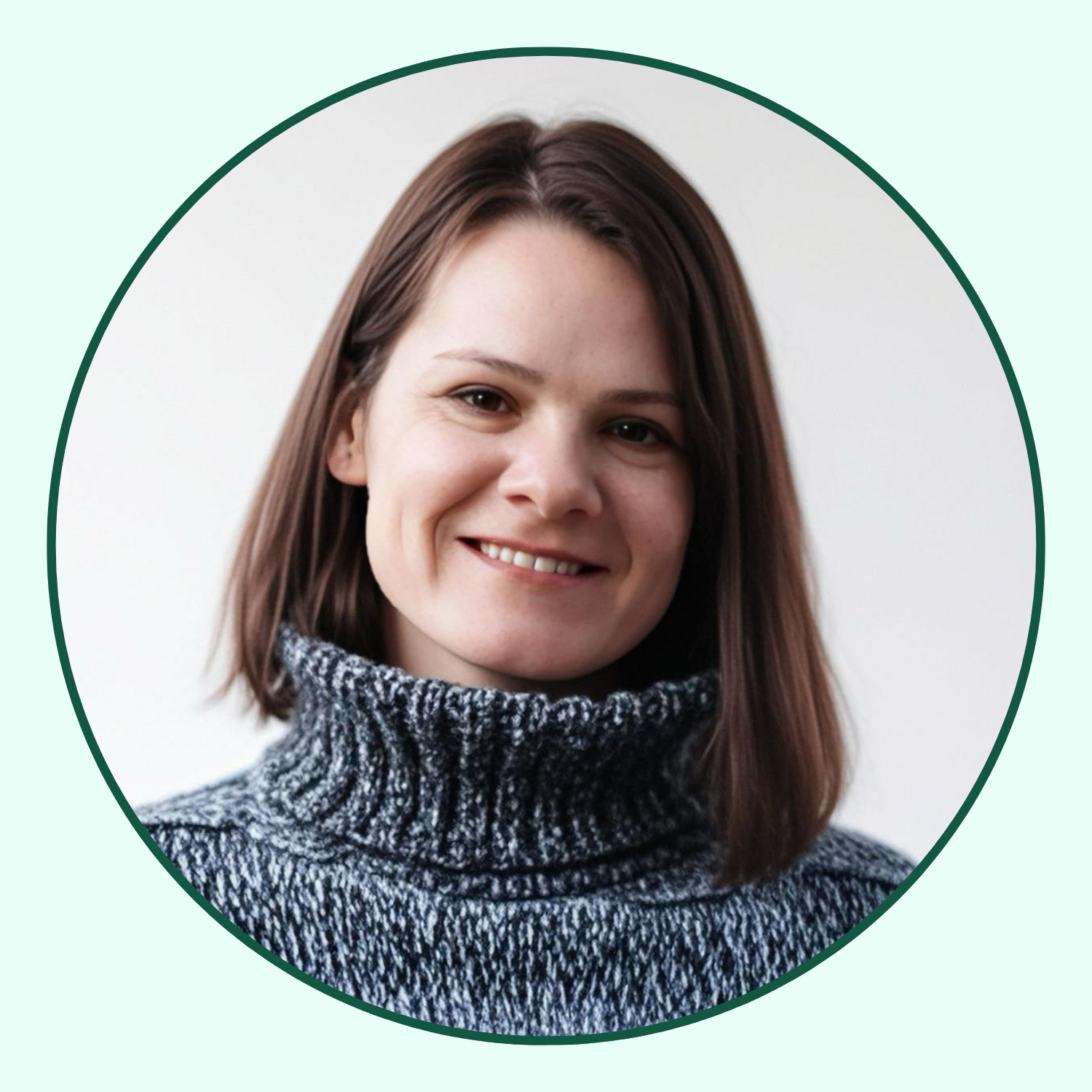 A woman with shoulder-length brown hair wearing a gray and black patterned turtleneck sweater, smiling against a plain white background.