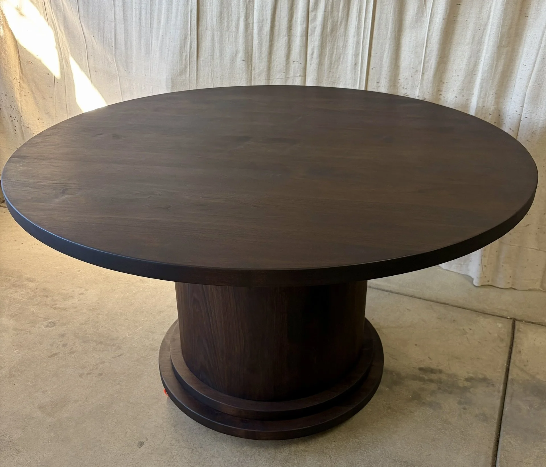 A round dark walnut hardwood wooden table with a pedestal base round made from solid walnut