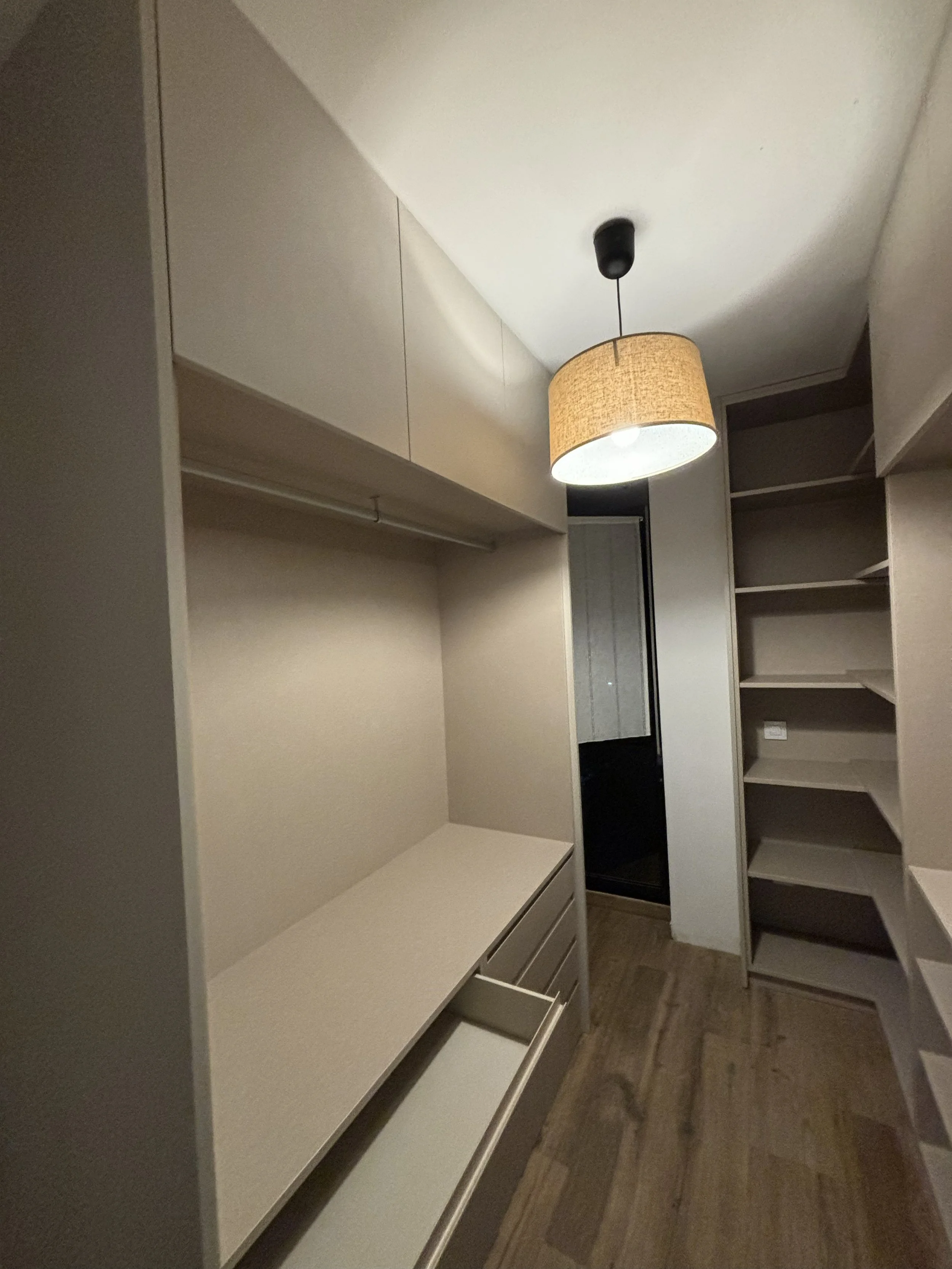 Armario de almacenamiento con estanterías y gavetas en una habitación iluminada con lámpara de techo.