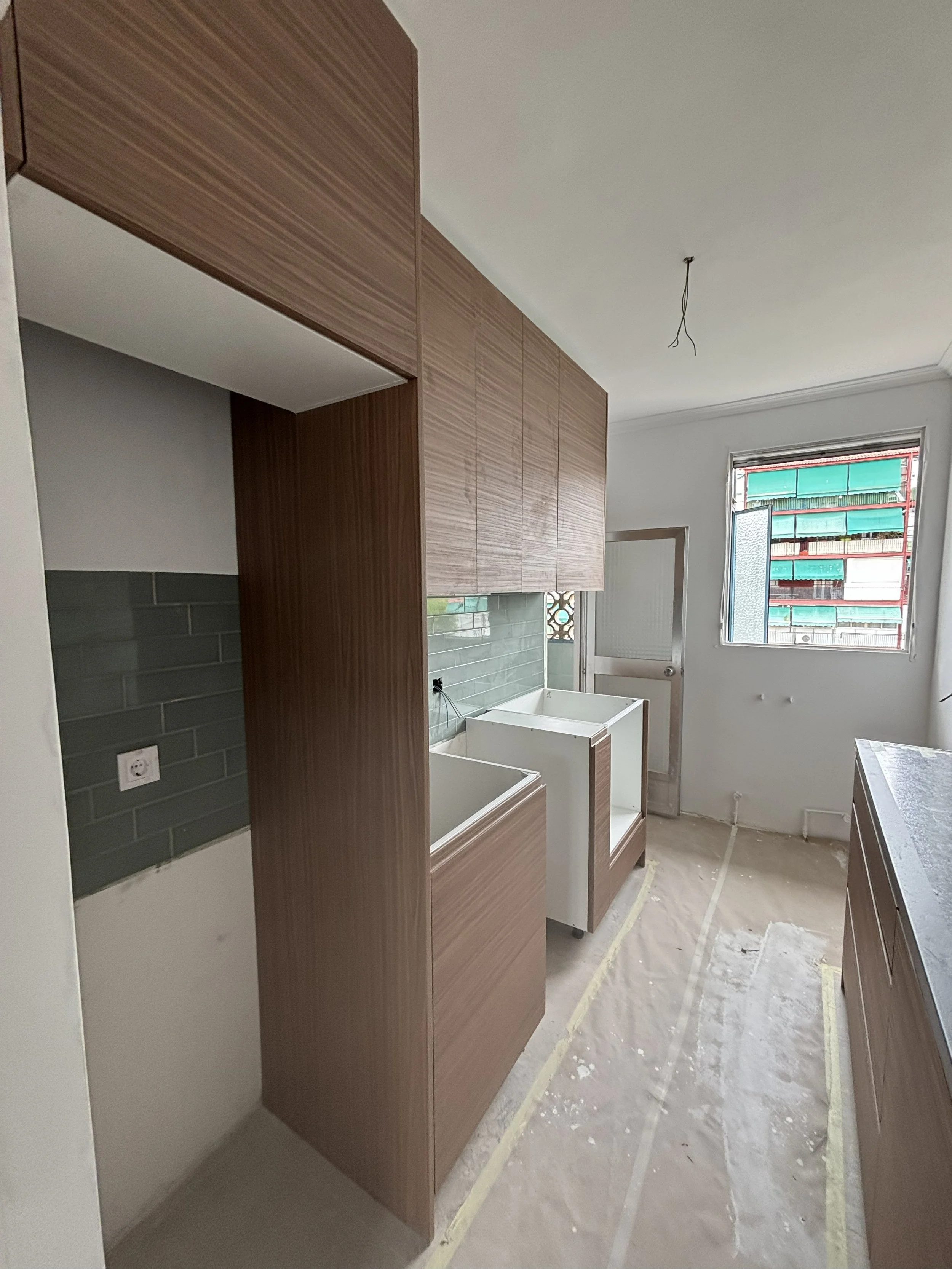 Cocina en construcción con gabinetes de madera, pared de loseta gris y ...