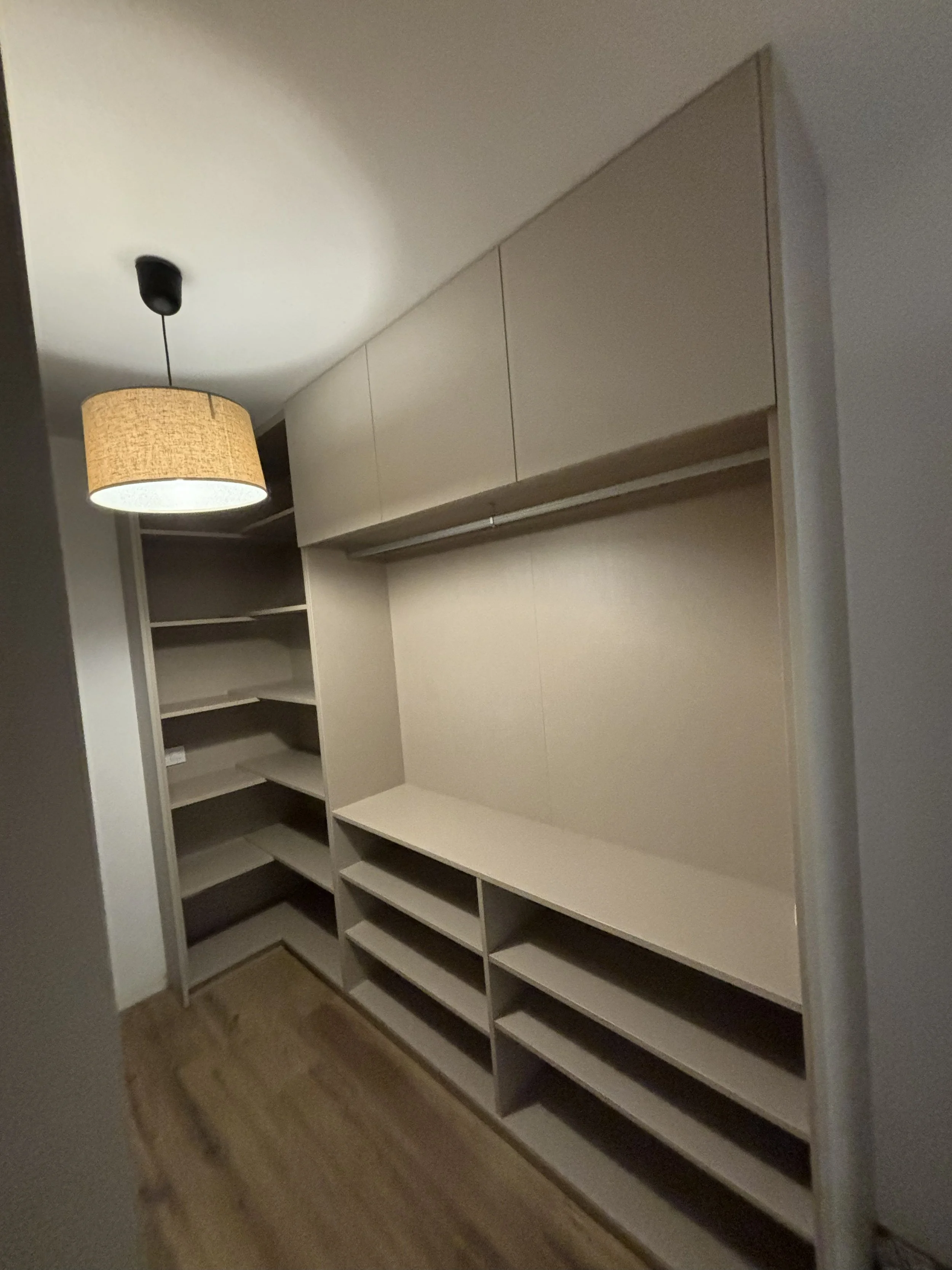 Armario empotrado con estantes y cajones, en una habitación con lámpara de techo y suelo de madera.