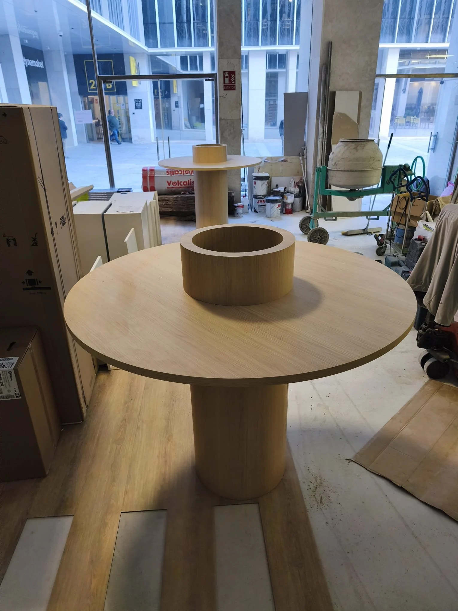 Una mesa de madera redonda en una tienda con una estructura circular en el centro.