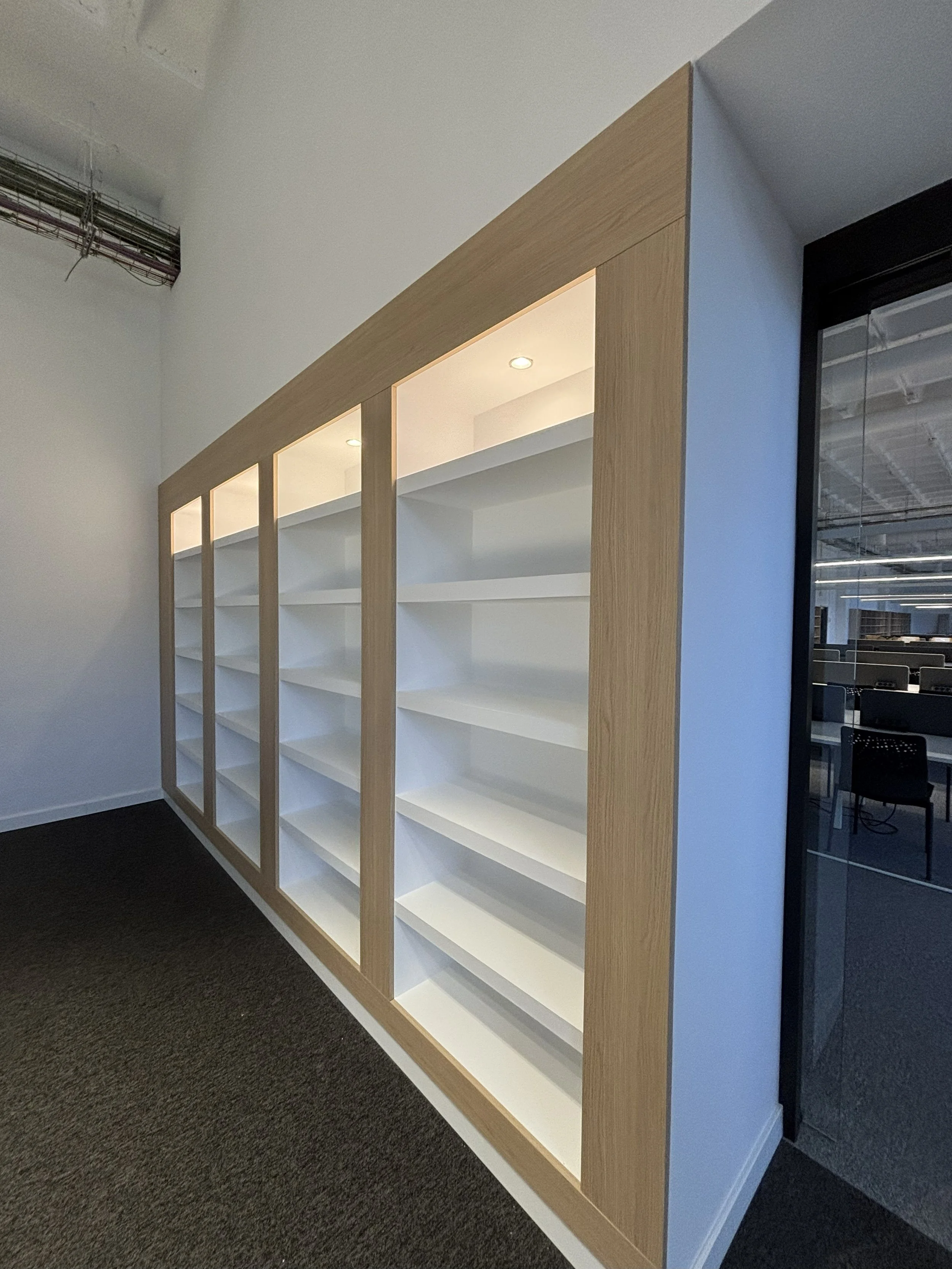 Estantería de madera con puertas de vidrio en un espacio de oficina moderno.