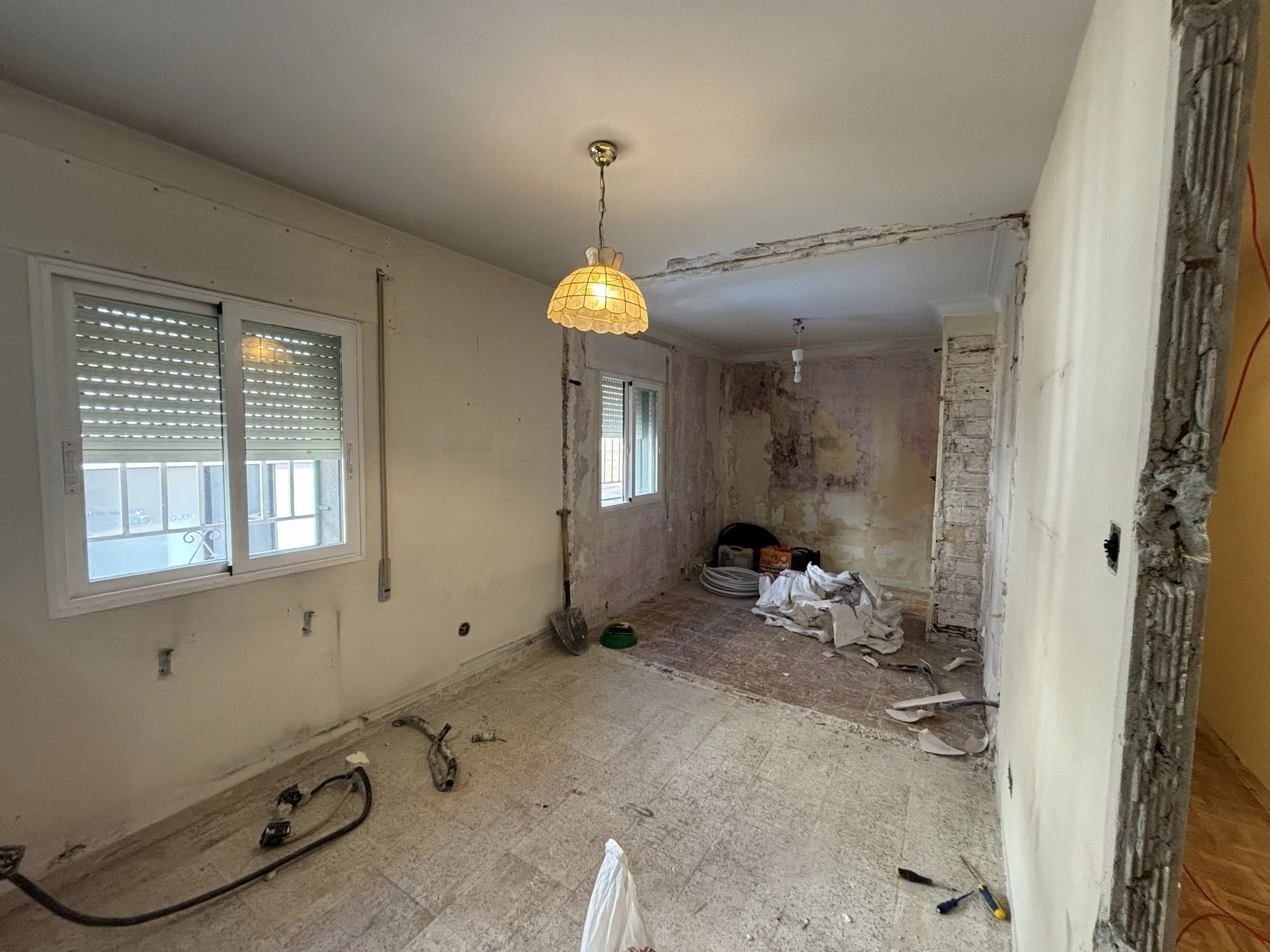 Interior de una habitación en renovación, con paredes en proceso de reparación y herramientas de construcción en el suelo.