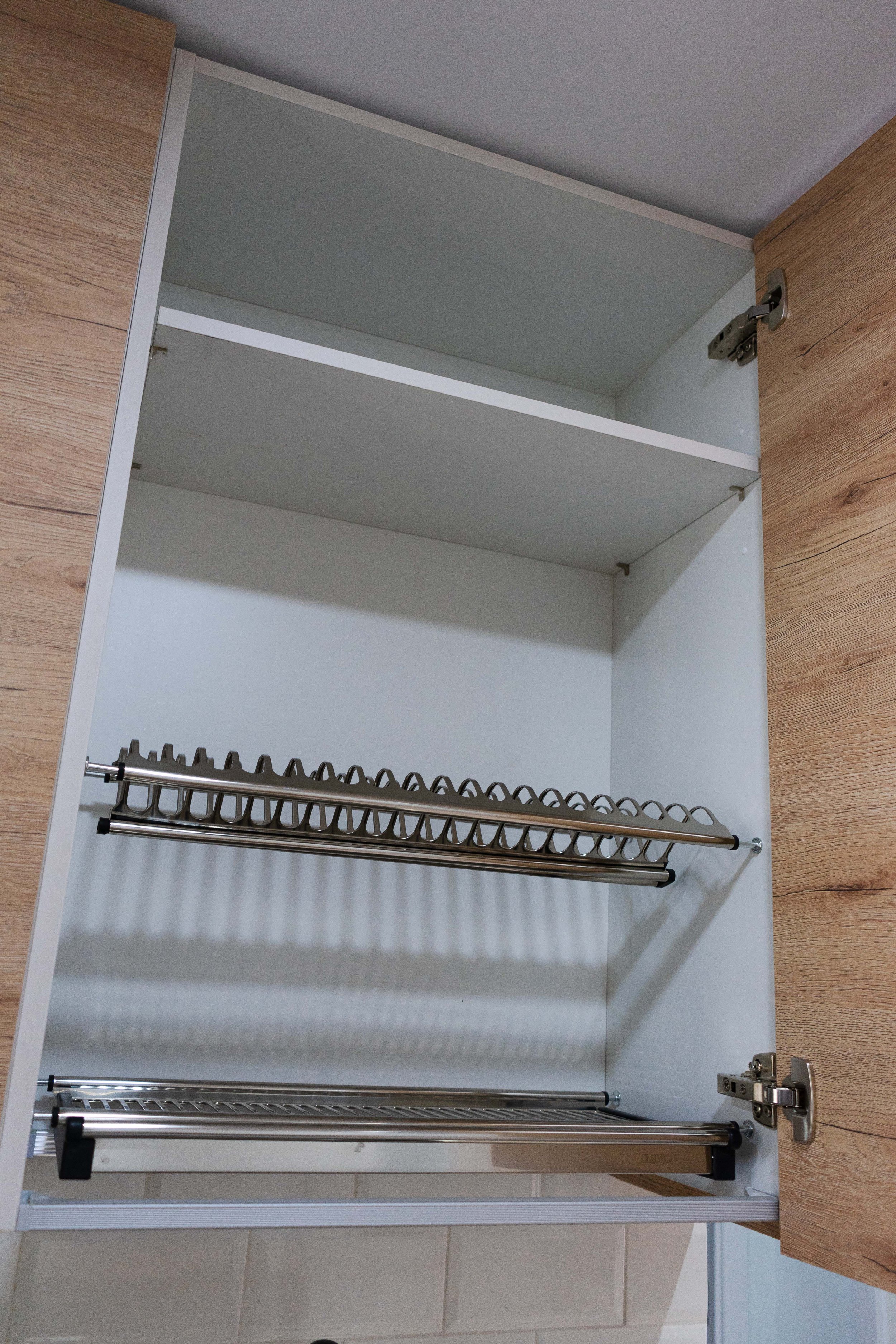 Gabinete de cocina abierto con estantes de madera y rejillas de metal, parcialmente vacío.